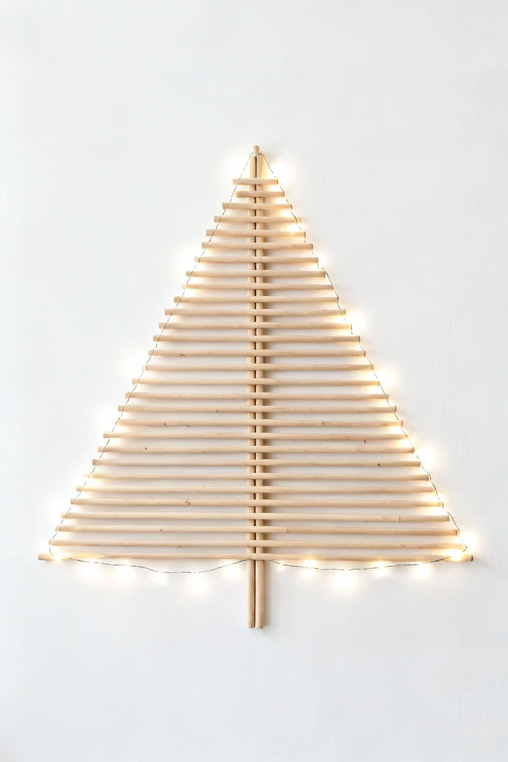 Minimalist wall-hanging Christmas tree made of wooden dowels and simple string lights