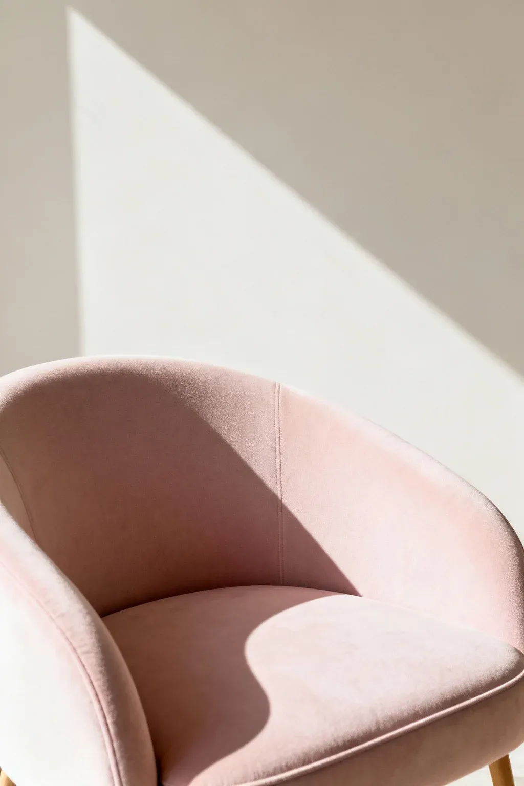 Curved Scandinavian accent chair in pastel upholstery against pale wall