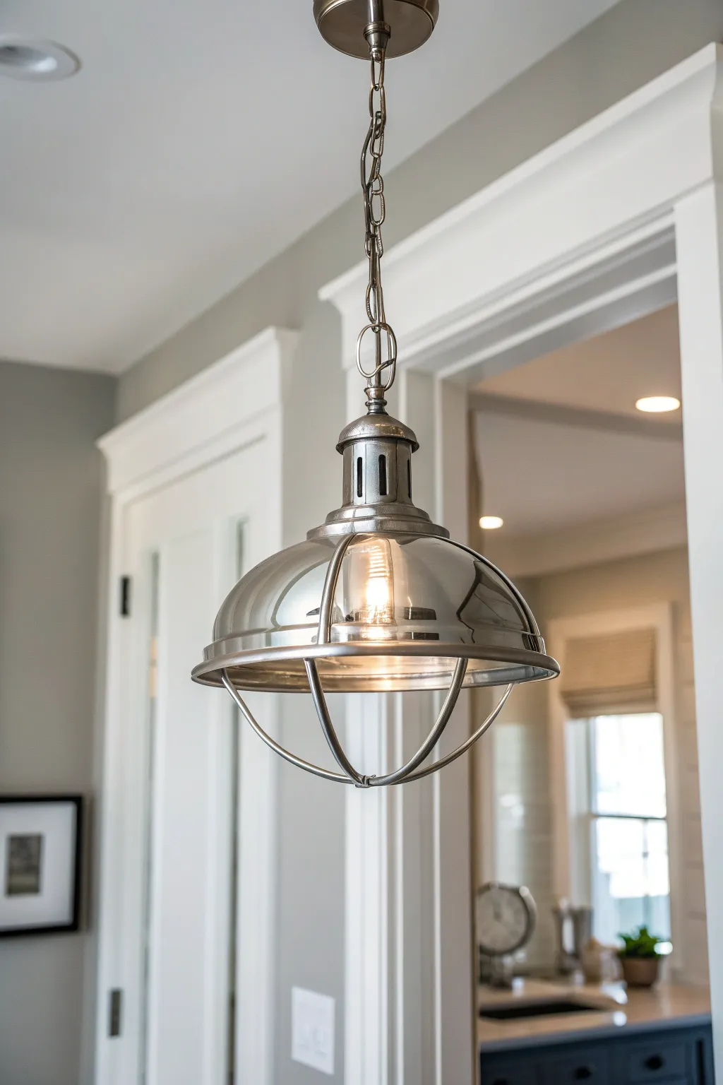 Sleek metallic pendant light hanging in a modern entryway with soft lighting.