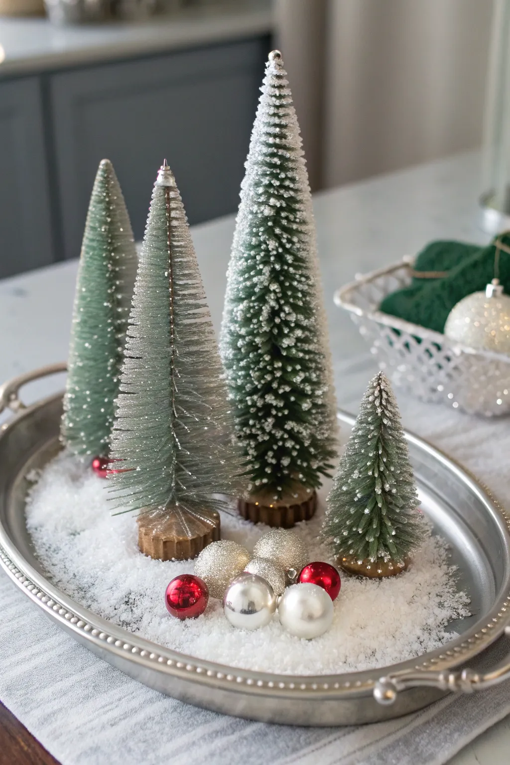 Vintage silver tray with bottlebrush trees, faux snow, and ornaments in soft winter light.