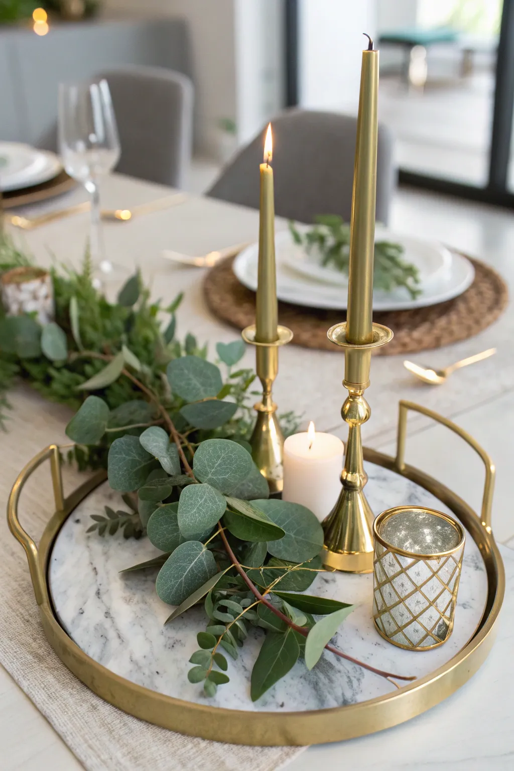 Marble tray with gold candleholders and eucalyptus greenery arranged elegantly.