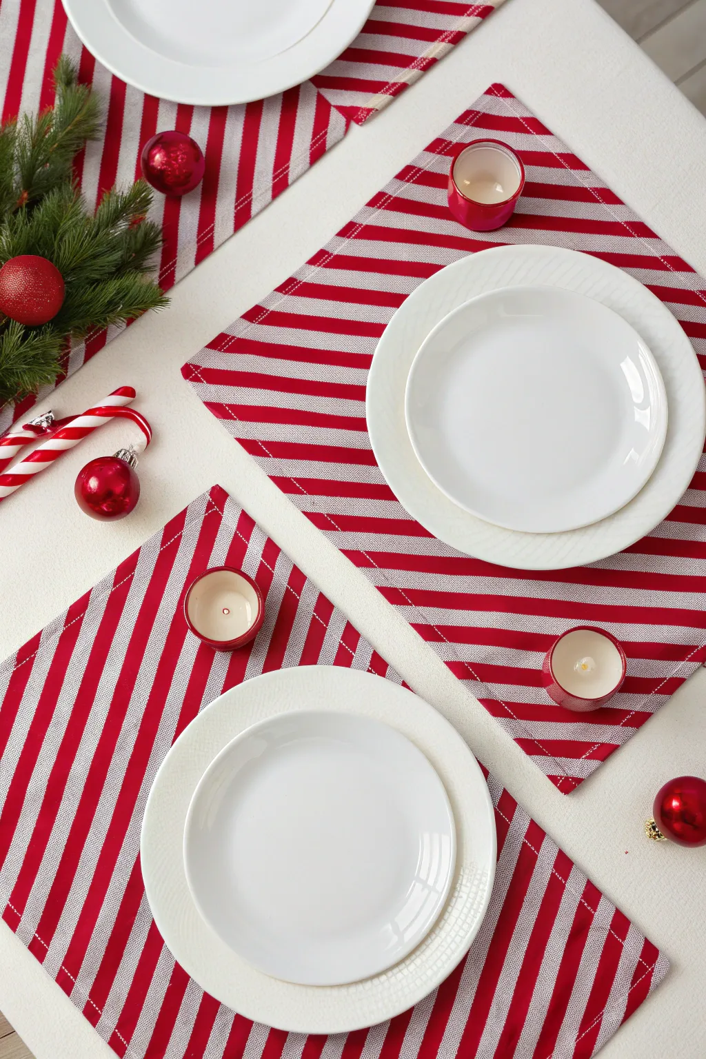 Red and white striped placemats with white plates and small red ornaments for a candy cane look