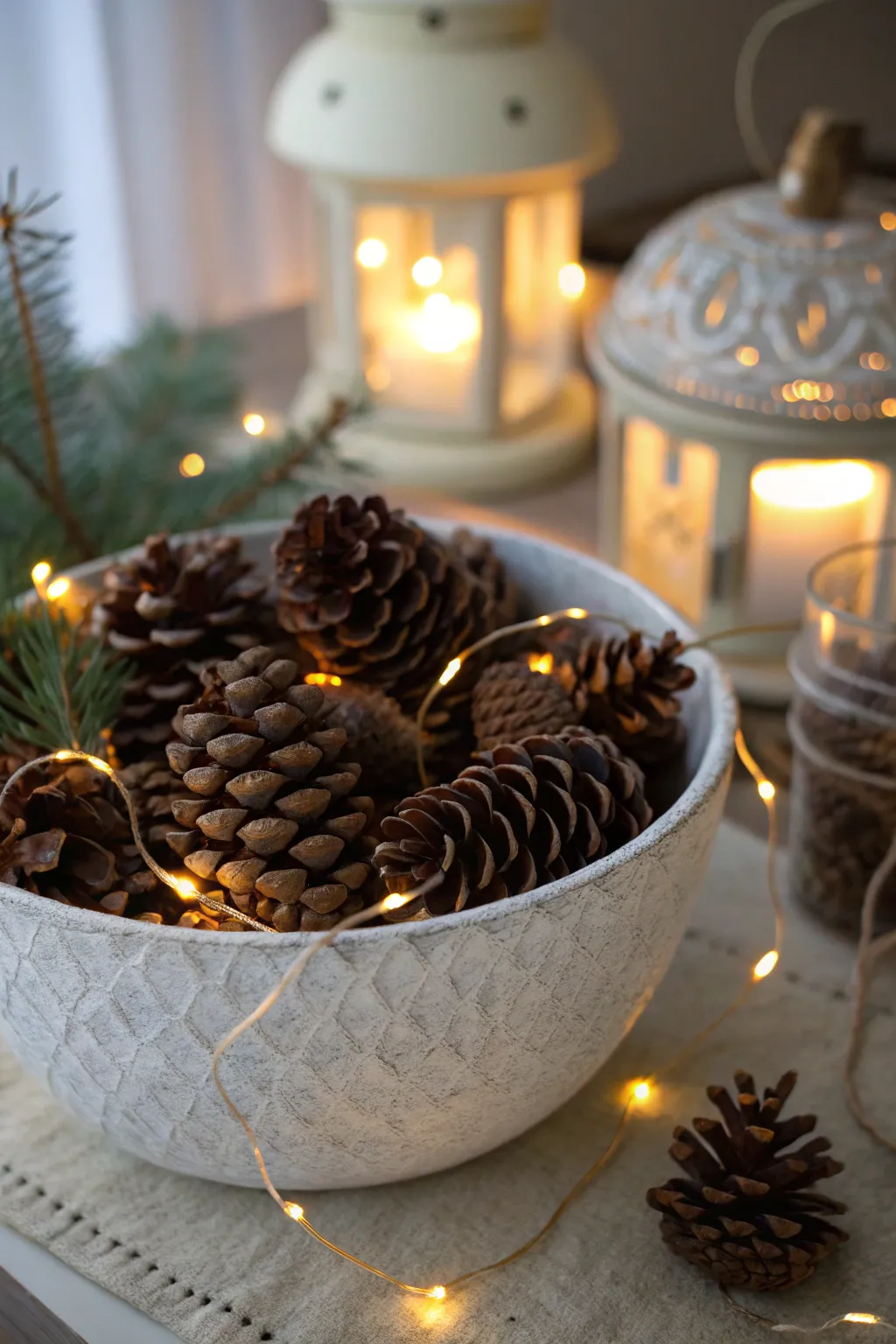 Wooden or metal bowl filled with pinecones and warm fairy lights on a holiday table