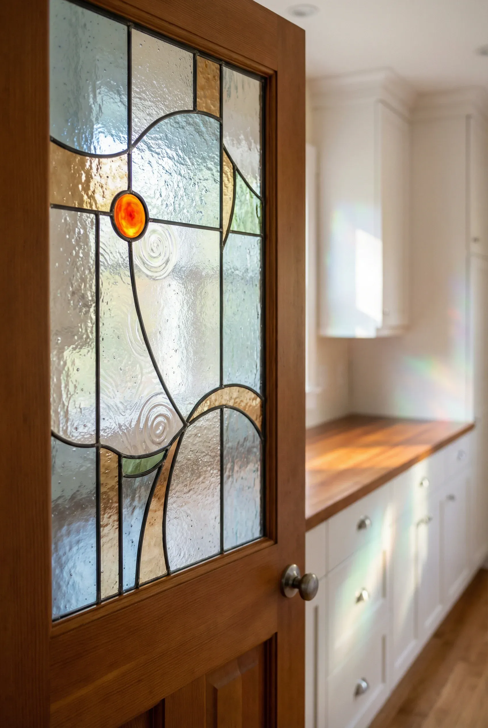 Whimsical stained glass inset in a pantry door glowing softly within a bright kitchen.