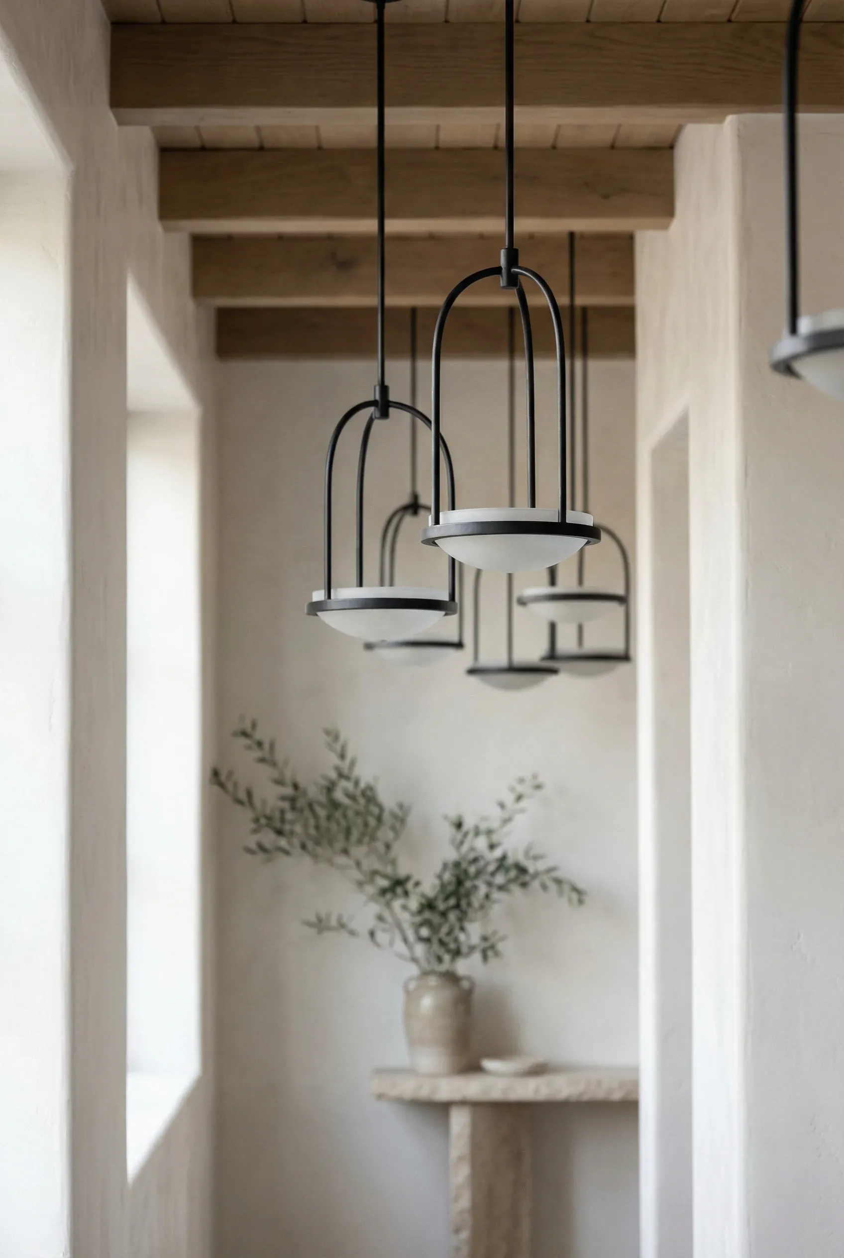 Minimalist wrought iron Mediterranean light fixtures with clean lines against soft-toned walls.