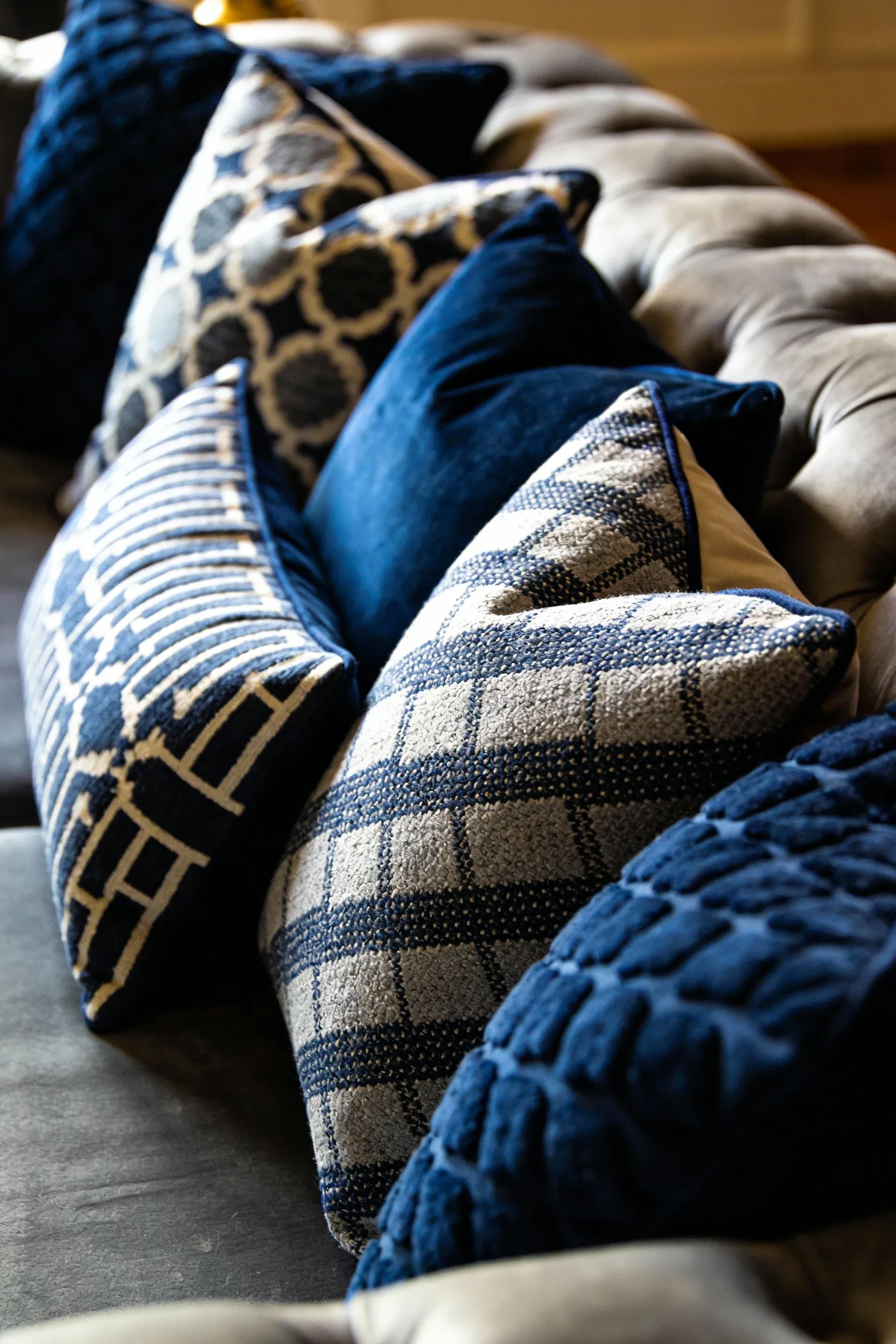Navy blue and gray decorative cushions on a plush sofa in a living room.