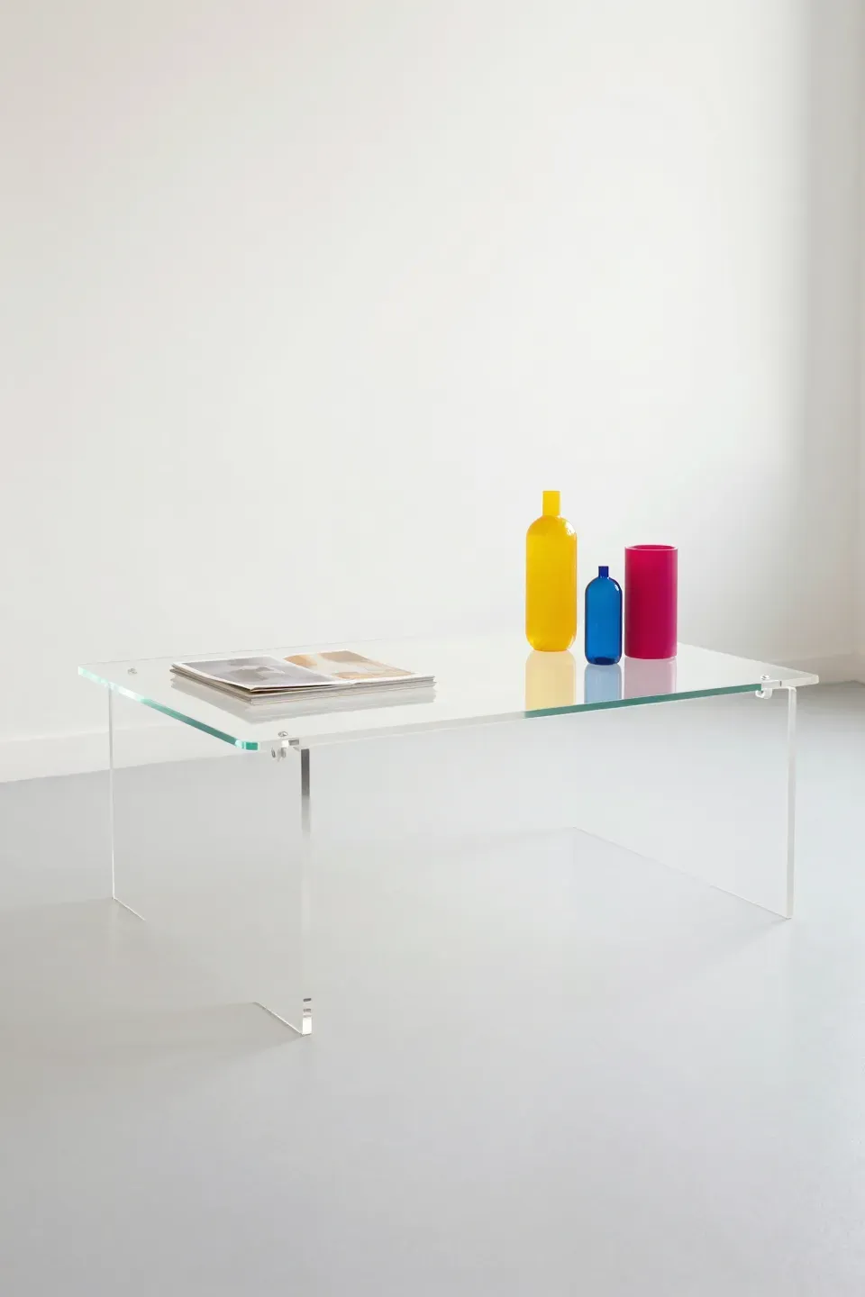 A modern acrylic coffee table with colorful decor pieces.