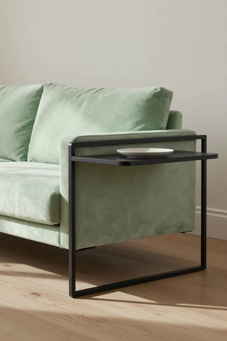 Light green couch accented with slim black metal side tables in a modern living room.