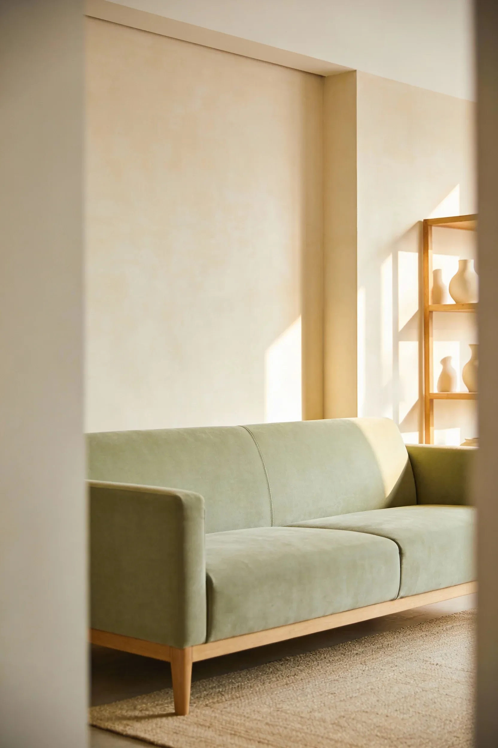 Light green couch against warm cream walls with soft natural lighting.