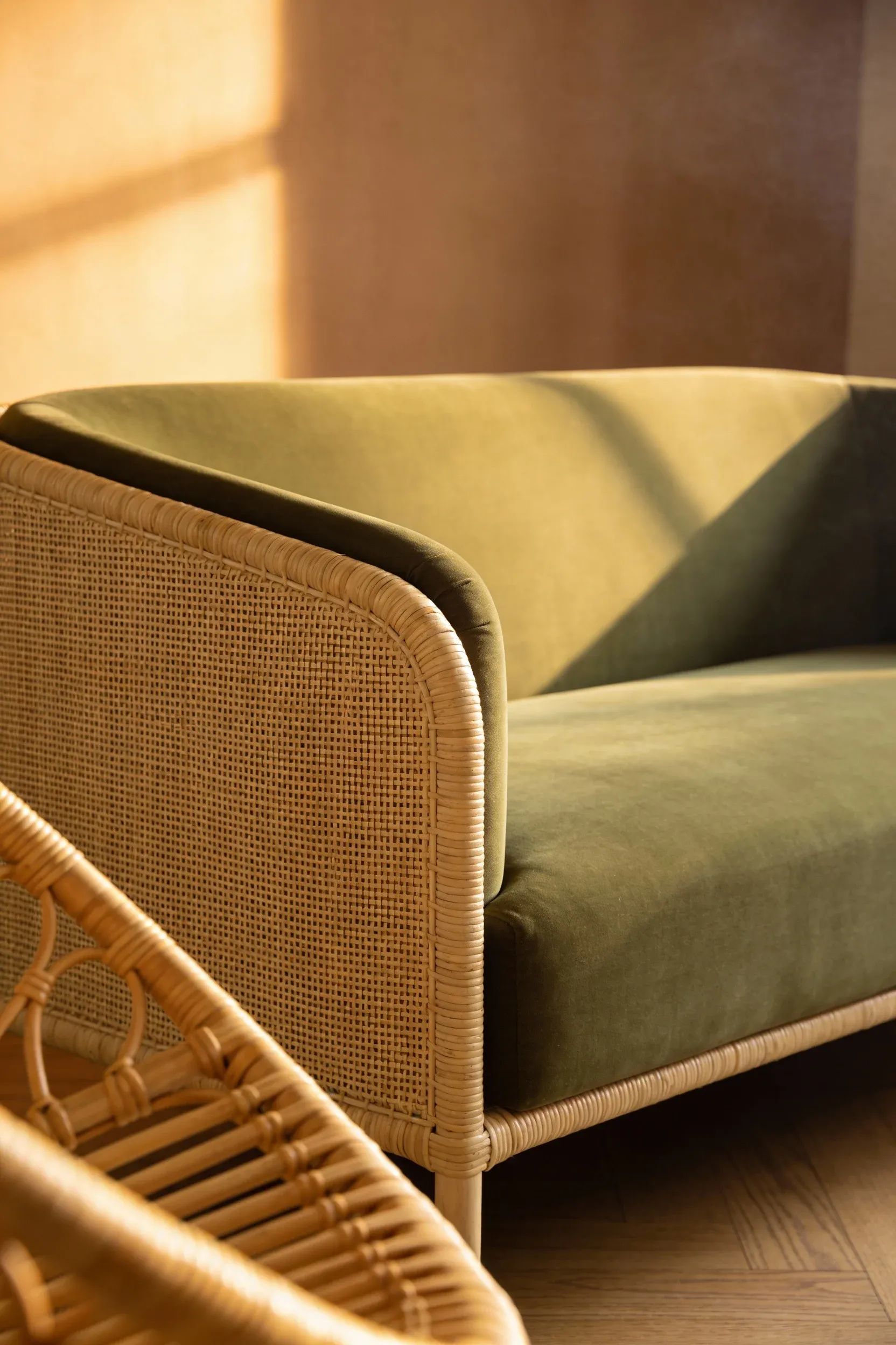 Olive green sofa paired with warm rattan accents in a cozy, earthy living room.