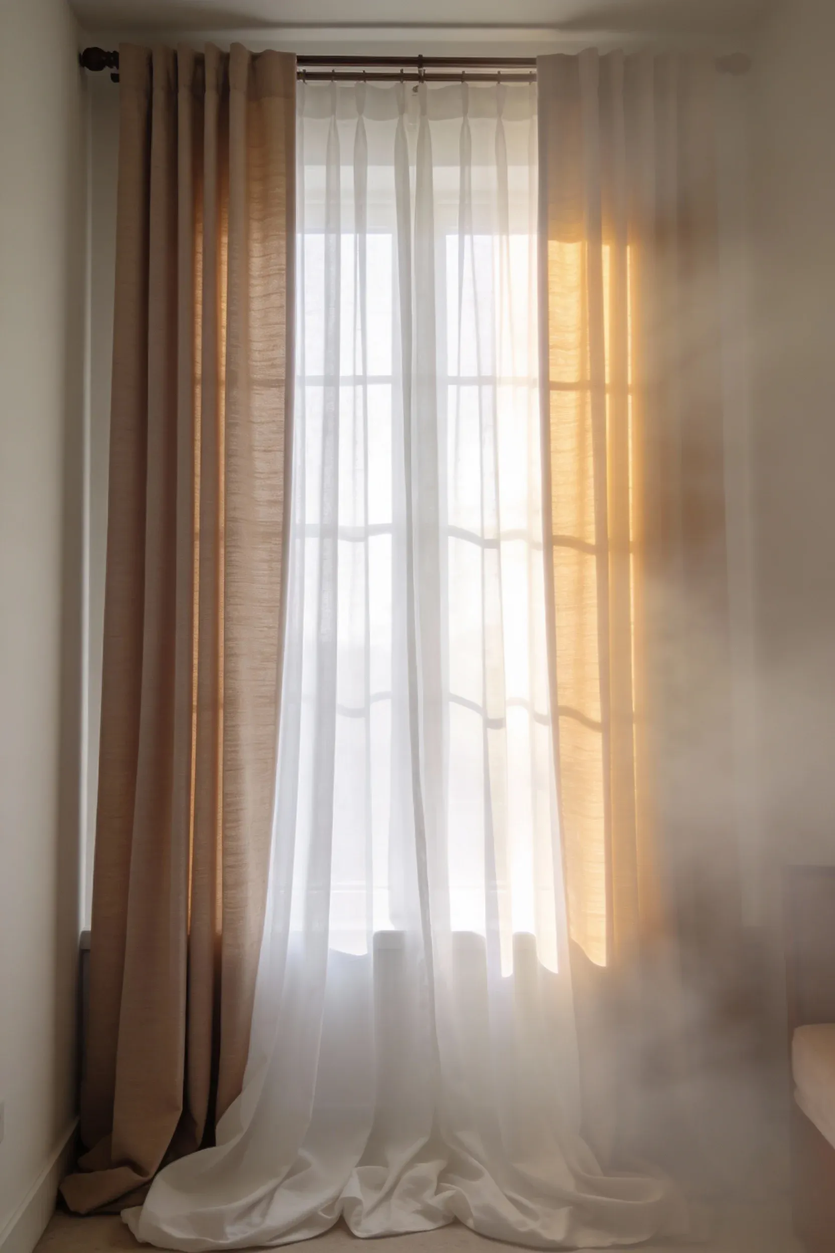 White sheer curtains layered with beige blackout panels in a soft, cozy bedroom.