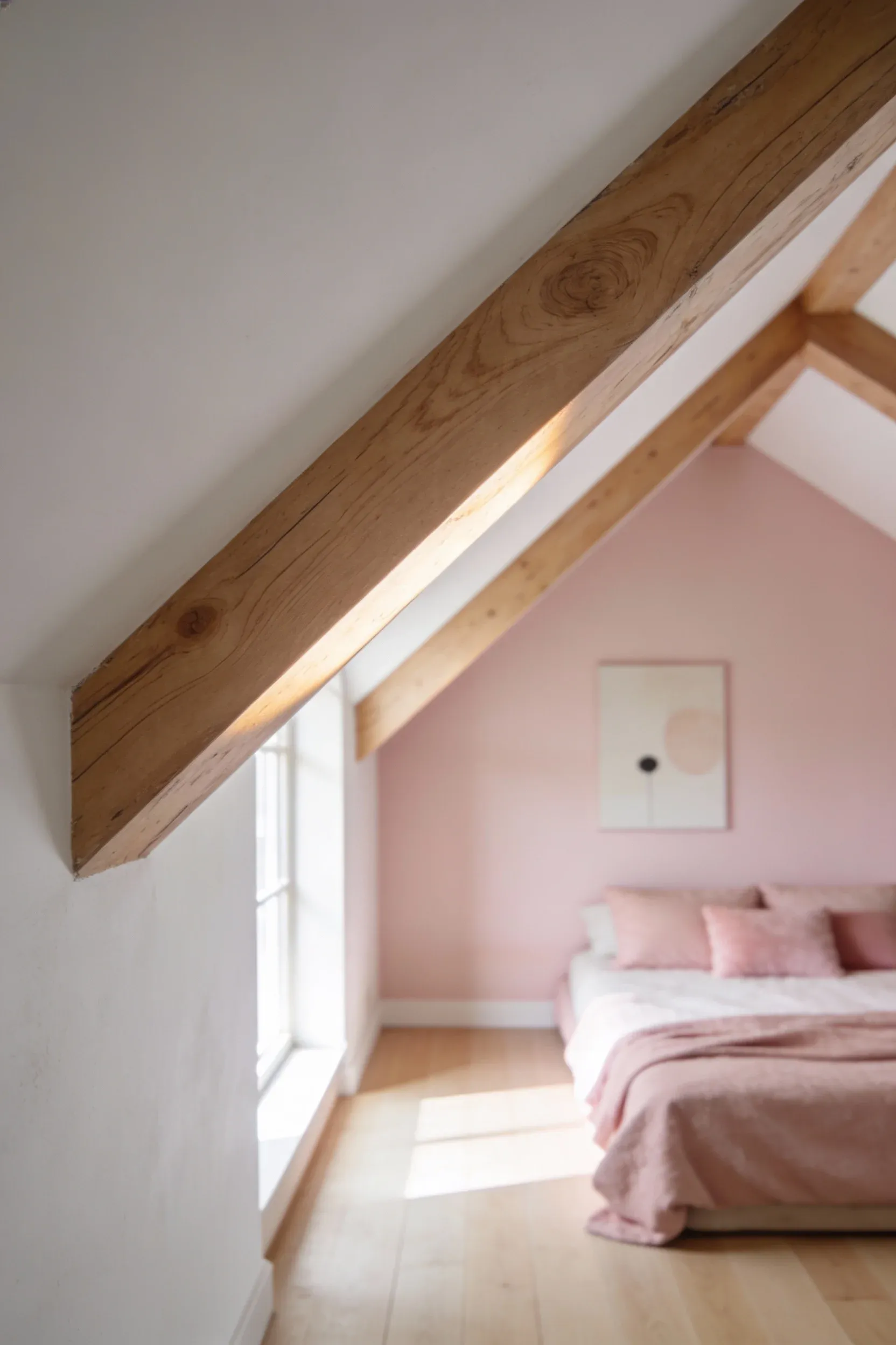 Exposed light-wood ceiling beams in a pink-themed bedroom, enhancing spaciousness and warmth.