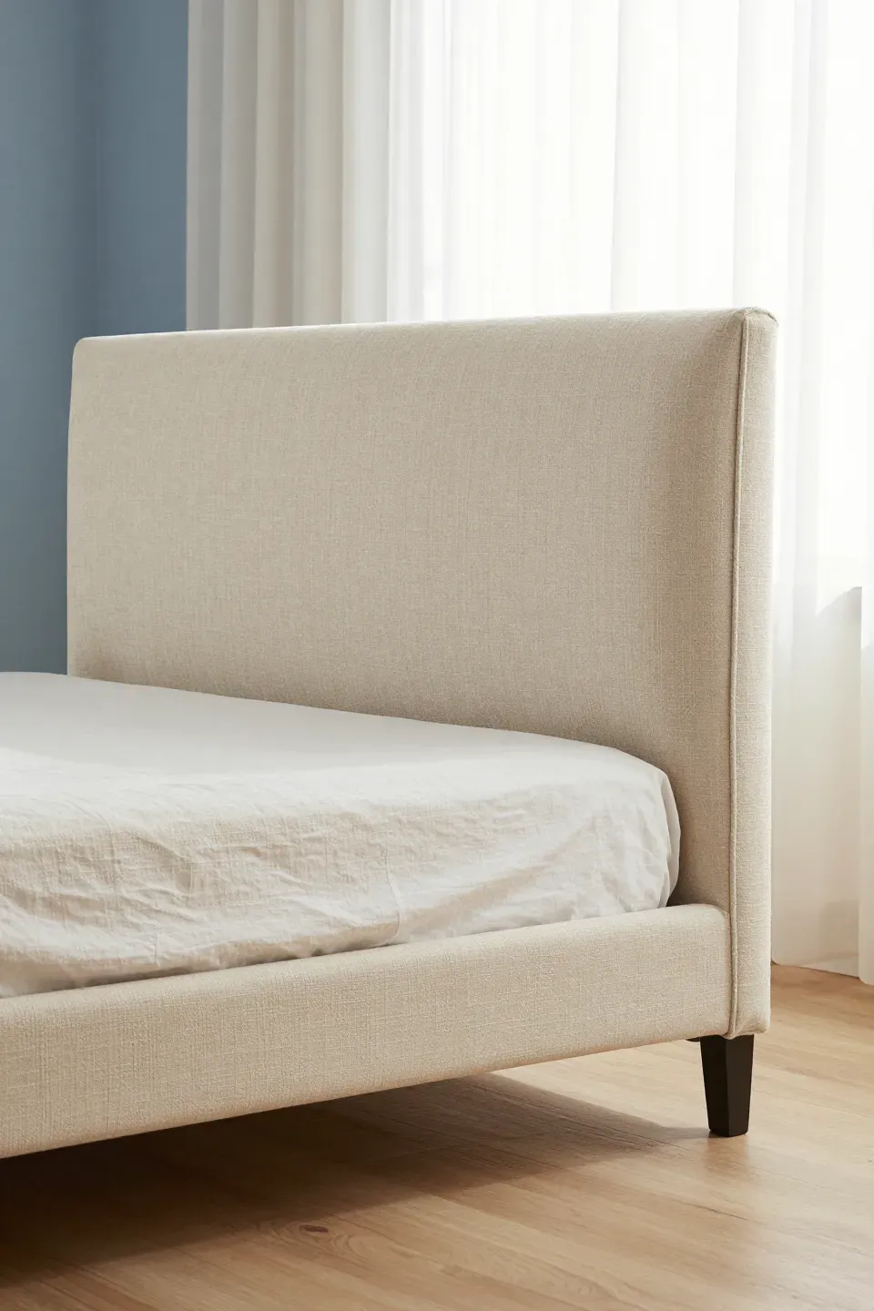 A stylish bedroom with a beige linen upholstered headboard and elegant decor.