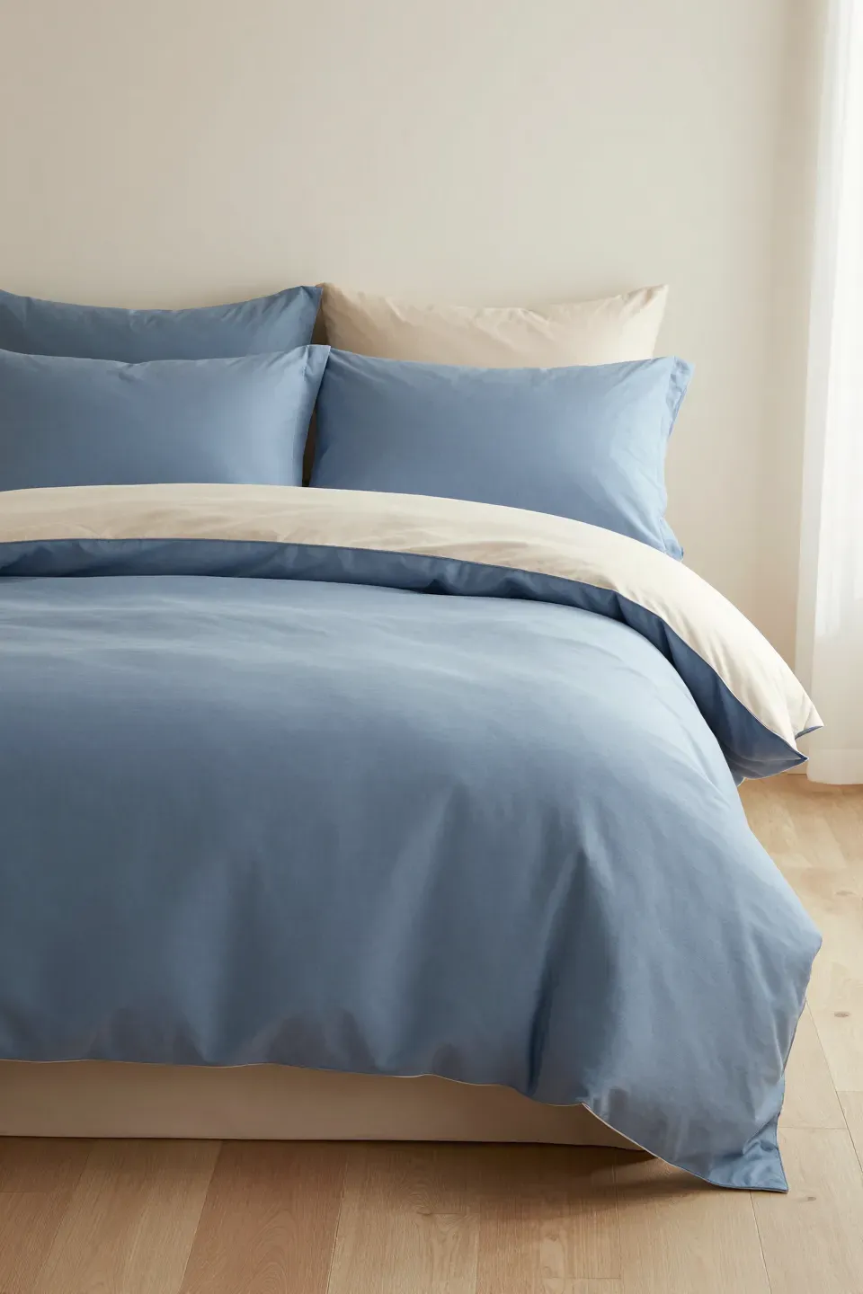 A luxurious bed with blue euro shams and a beige duvet in a serene bedroom setting.