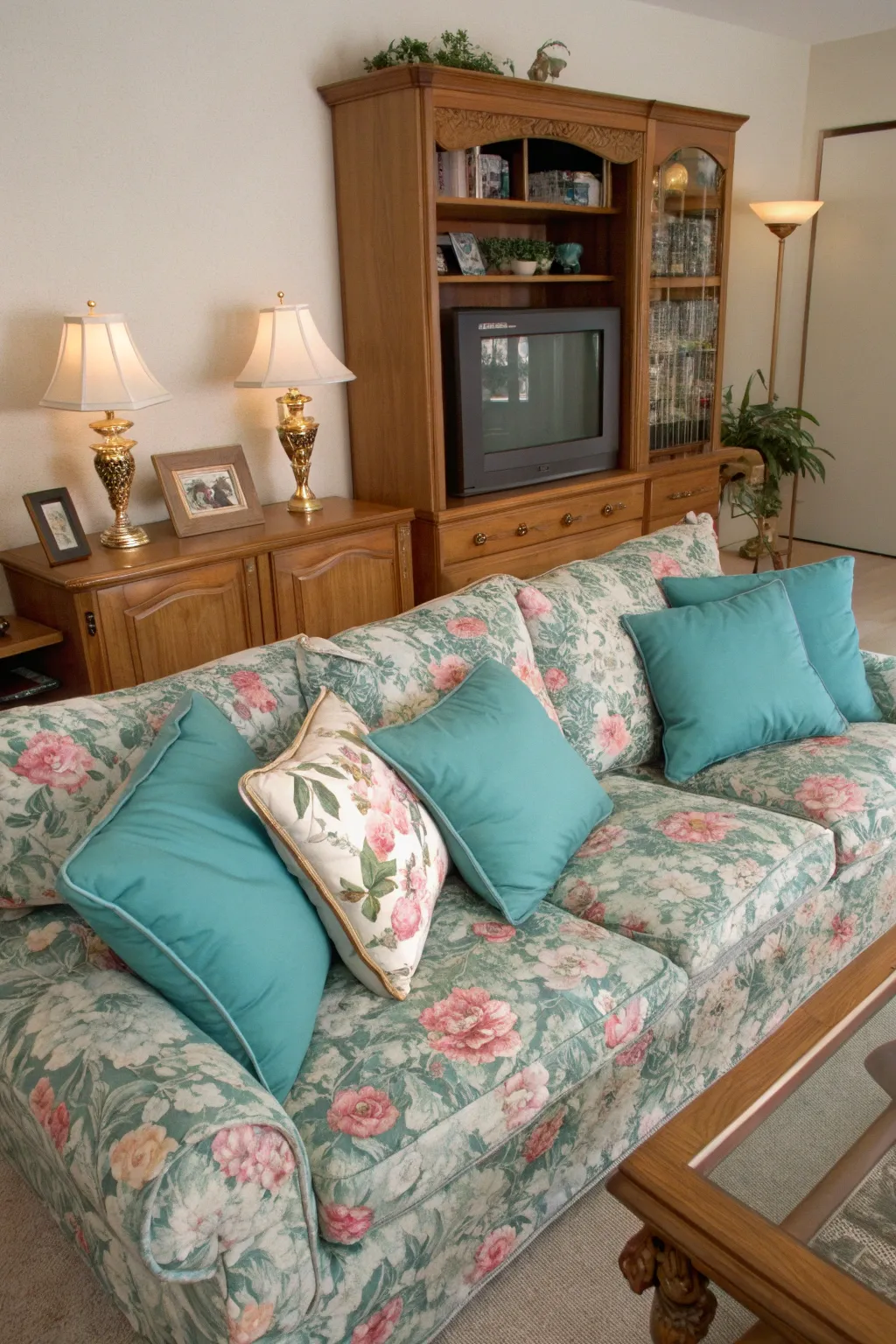 A cozy 1990s living room featuring faded teal and floral throw pillows.
