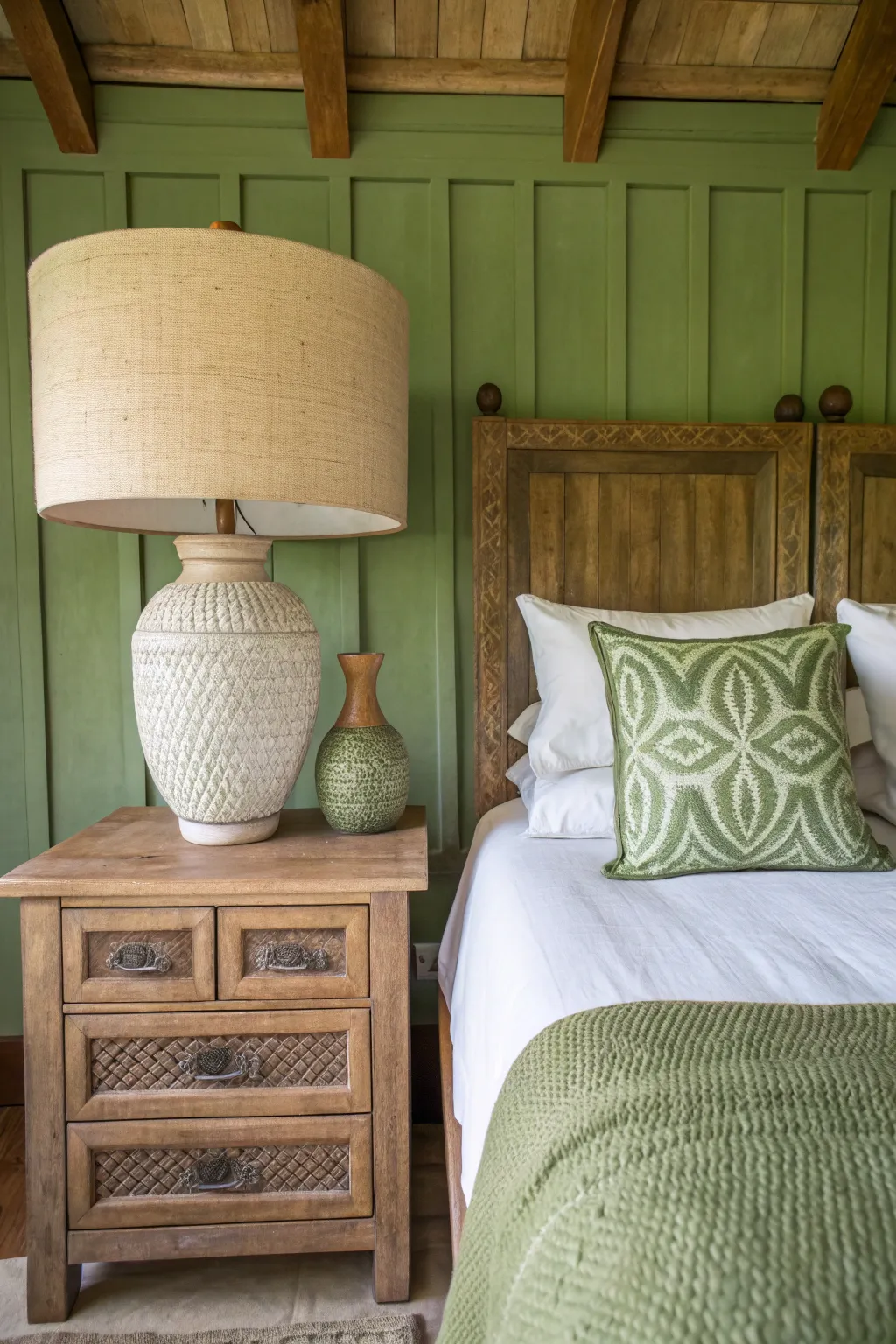 Two textured clay lamps with linen shades on nightstands in a warm, green-toned bedroom.