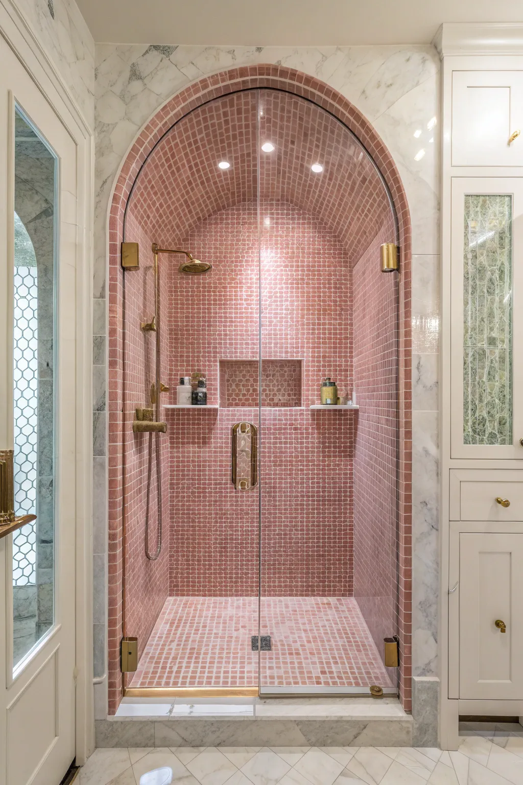 An arched shower niche with pink penny tiles set against a white tiled wall in a modern bathroom.