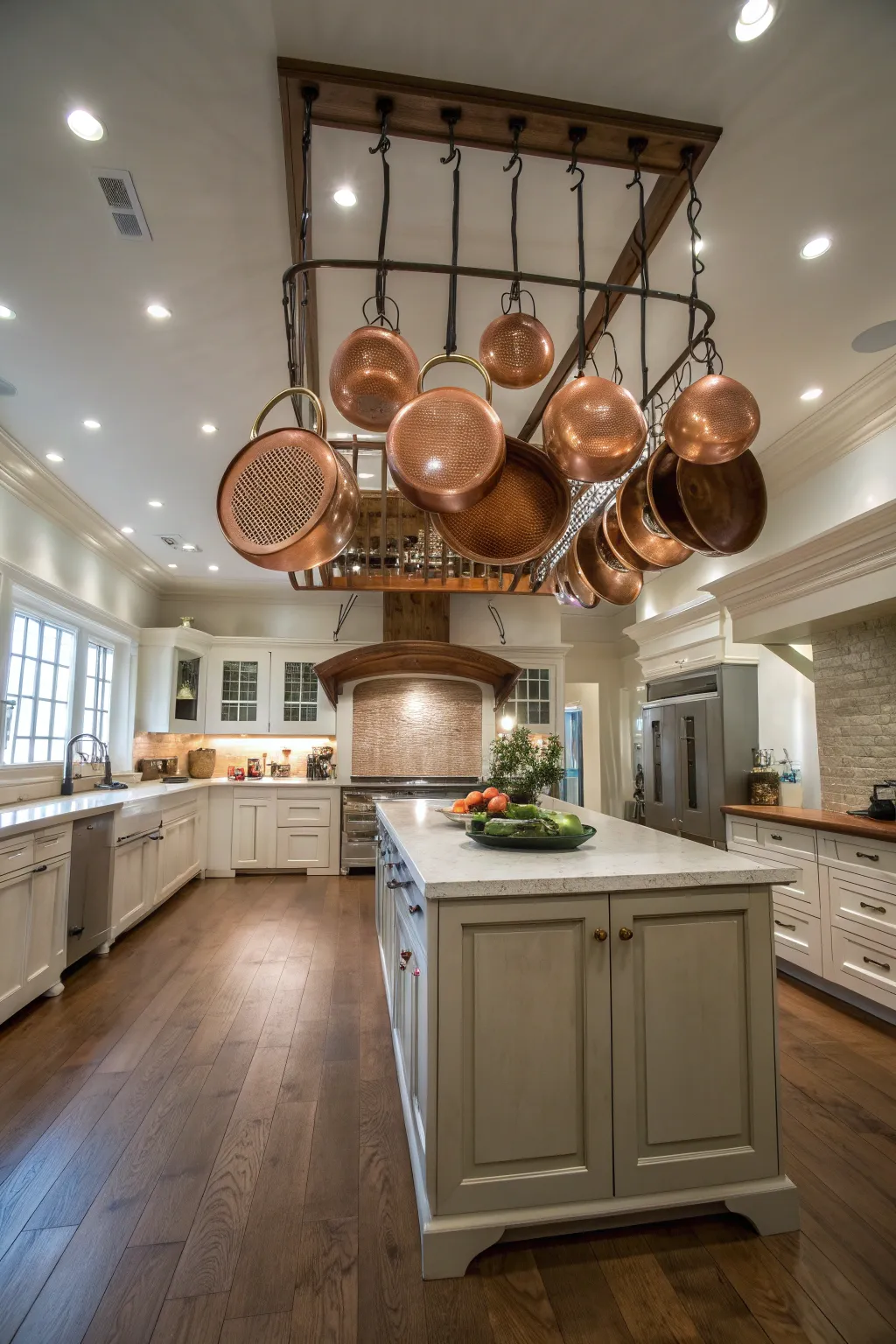 Hammered copper pots hanging from a ceiling rack in a bright farmhouse kitchen.