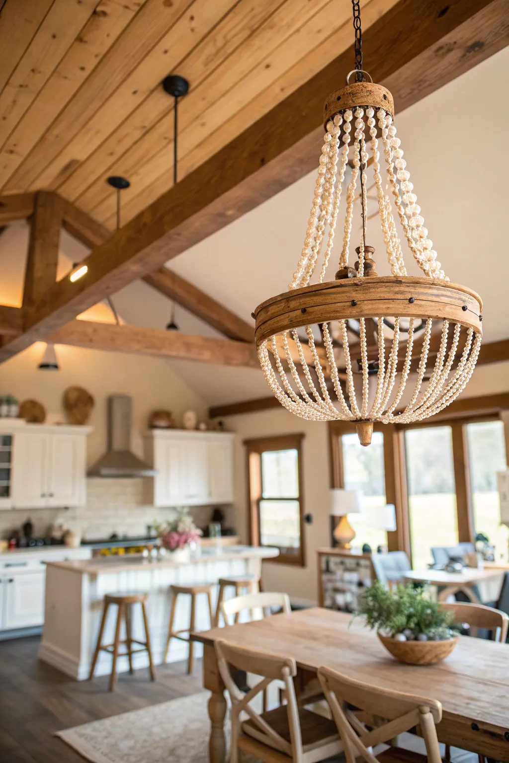 A farmhouse boho kitchen featuring a large wood-beaded chandelier hanging over a rustic dining table.
