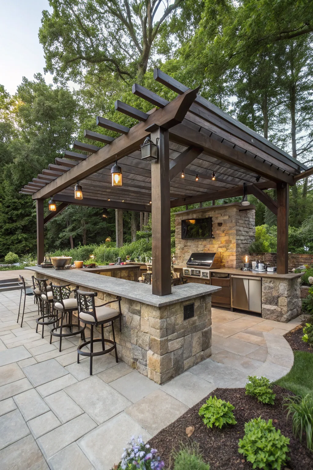 A luxury wooden corner pergola bar with stone counters and hanging pendant lights in a sunny backyard.