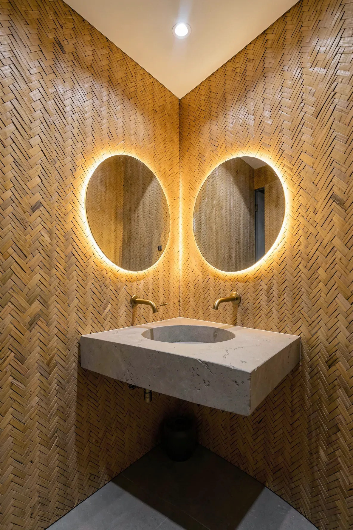 A luxury powder room with walls finished in a detailed bamboo herringbone woven pattern.
