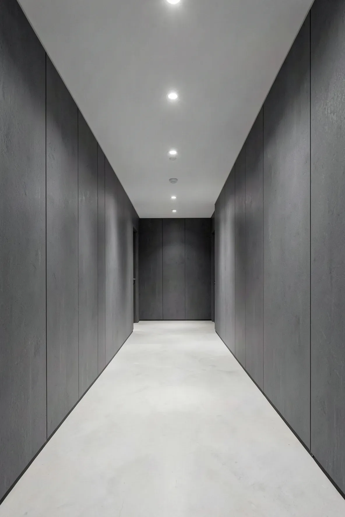 Sleek hallway with charcoal gray matte pressed bamboo fiber wall panels and recessed lighting.