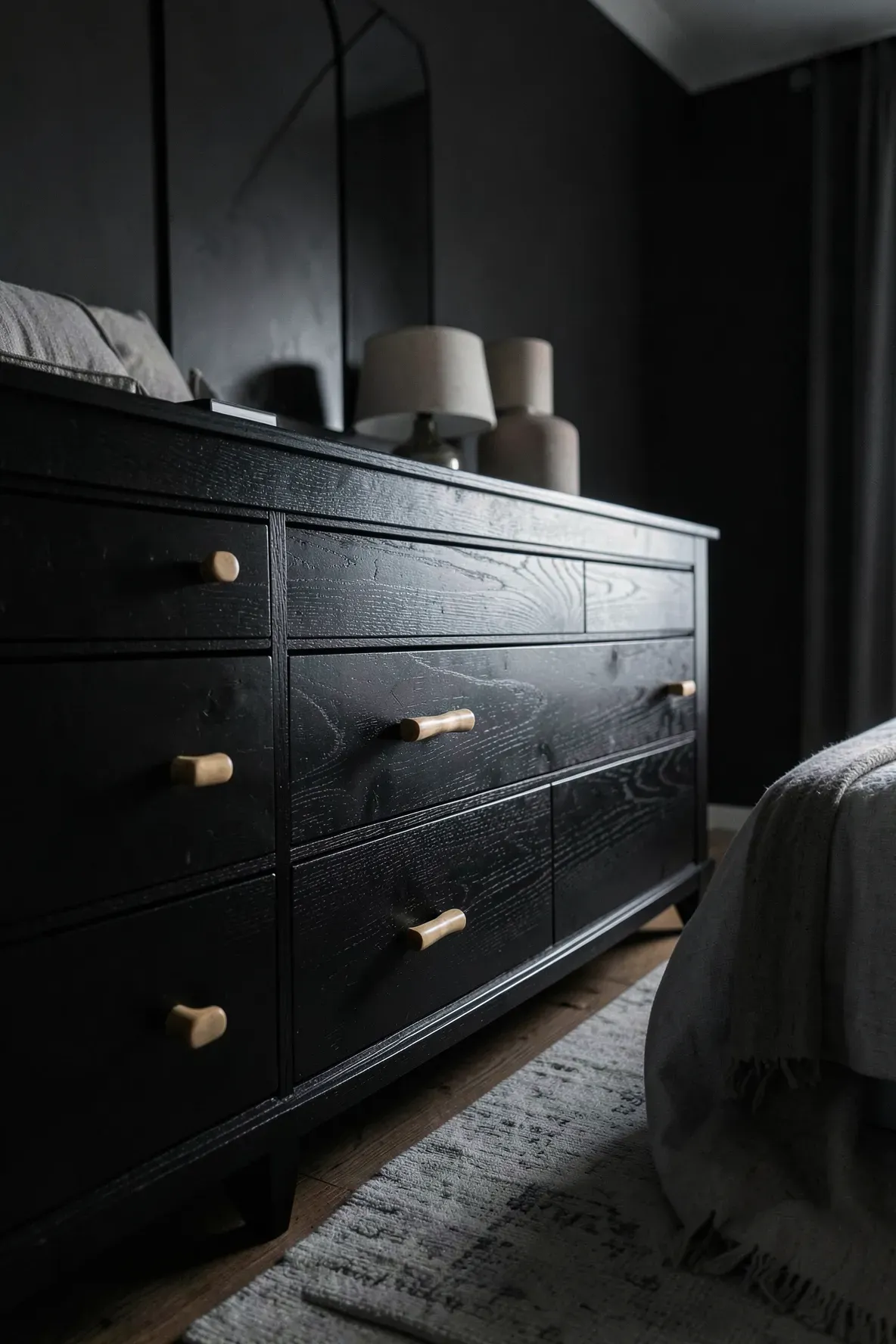 A black oak dresser with small bamboo drawer pulls in a stylishly designed bedroom.