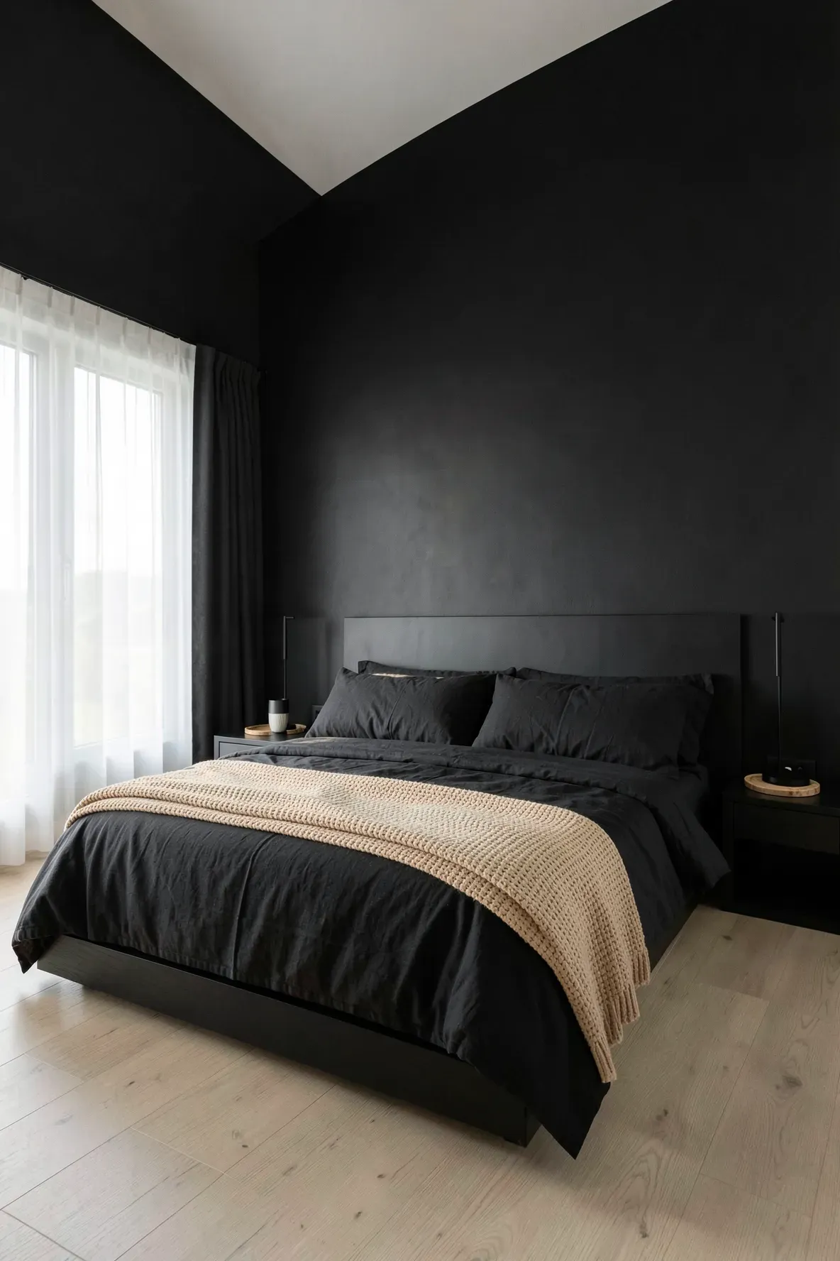 A modern bedroom featuring black linen bedding layered with a textured tan bamboo blanket.