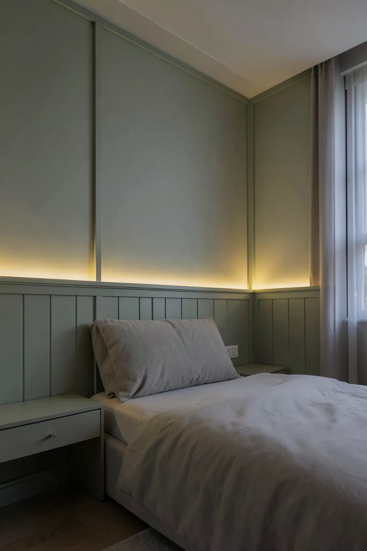 Sage green wall panelling in a bedroom illuminated by soft, warm integrated LED lighting.