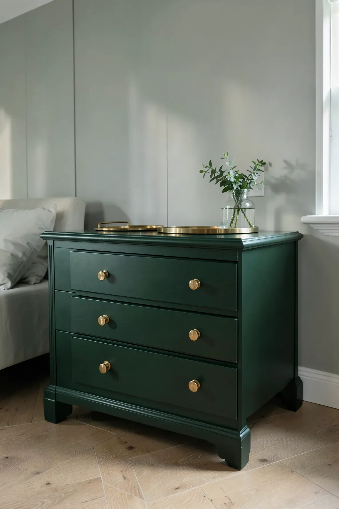 A deep forest green dresser with elegant brass handles in a stylishly designed bedroom.