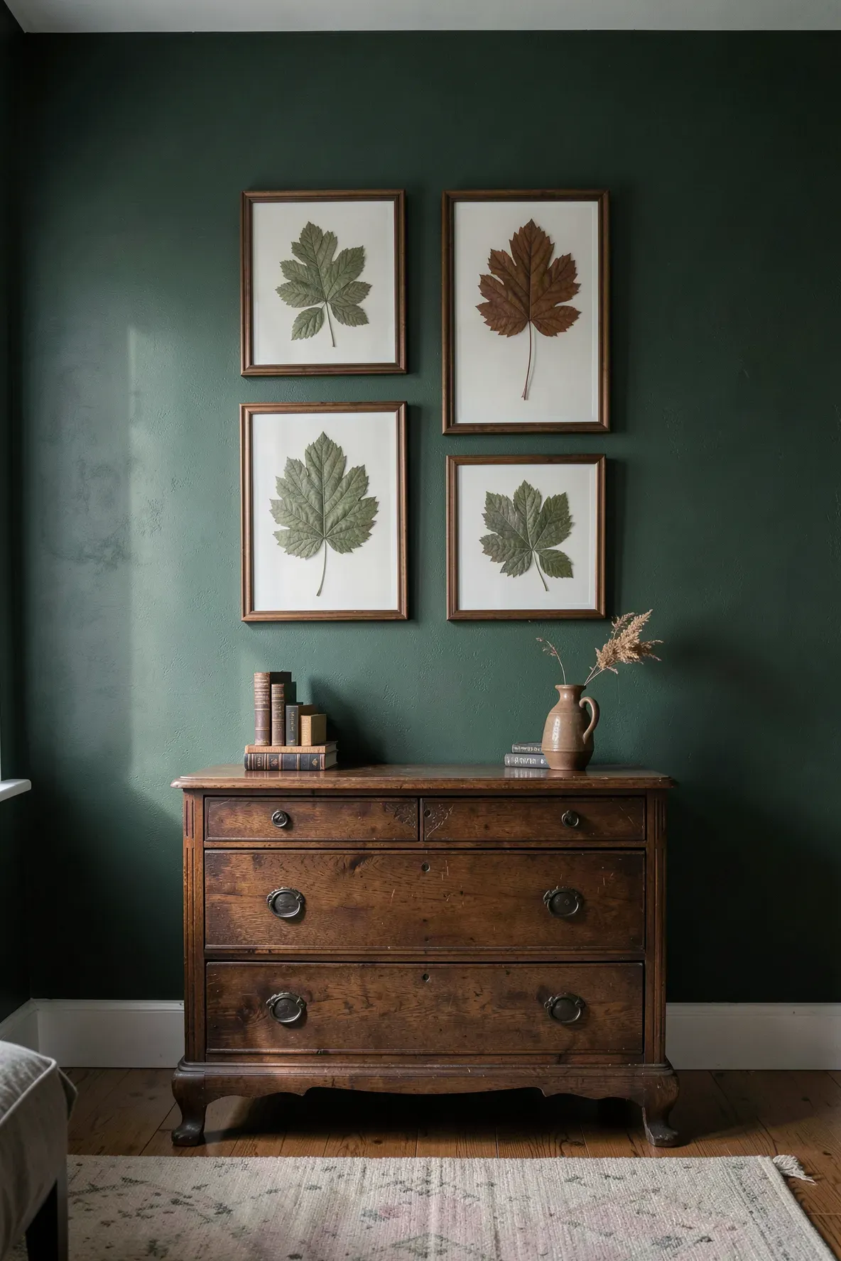 Pressed botanical leaves in floating glass frames displayed on a dark green bedroom wall.