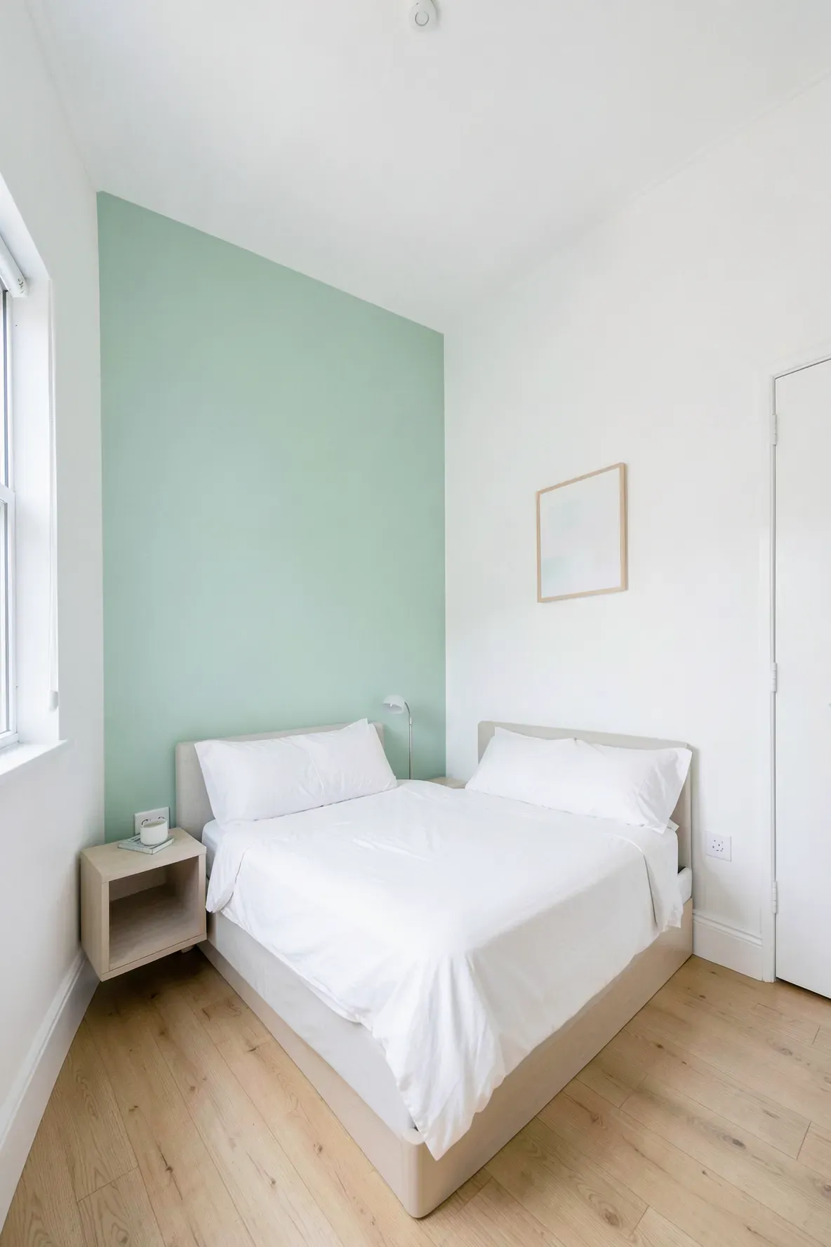 A small, bright bedroom with a seafoam green accent wall and white decor to create a spacious feel.