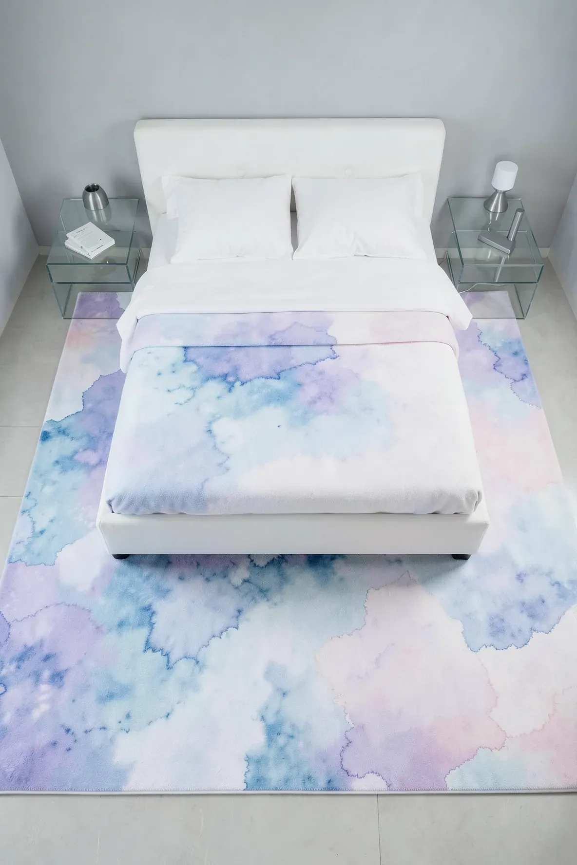 A serene bedroom featuring an abstract watercolor rug with soft blue and pink tones.