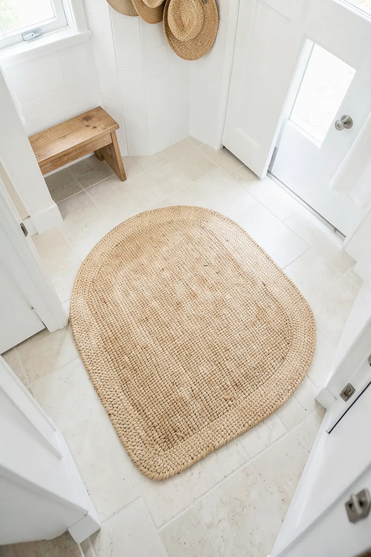 A natural woven reed floor mat on a light tile floor in a bright coastal room.