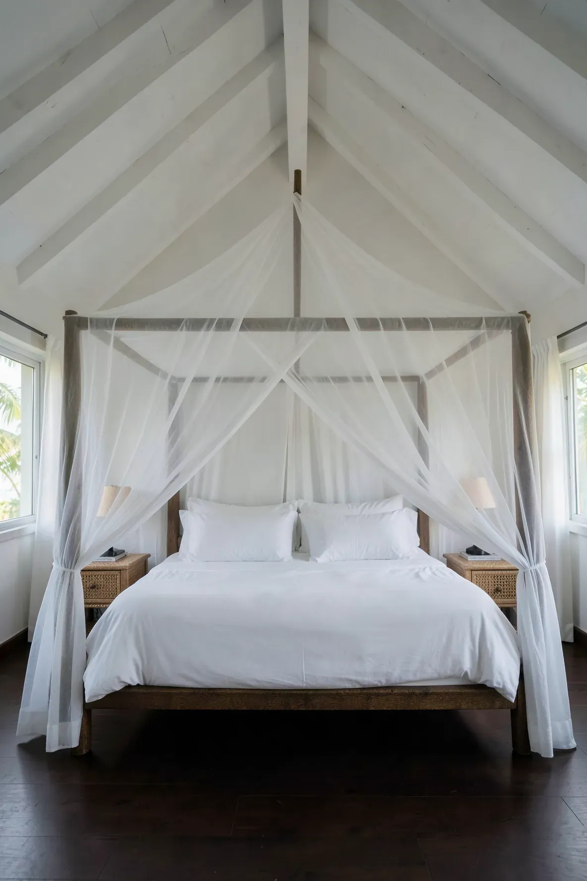 A dreamy white sheer canopy netting draped over a bed in a tropical-style coastal bedroom.