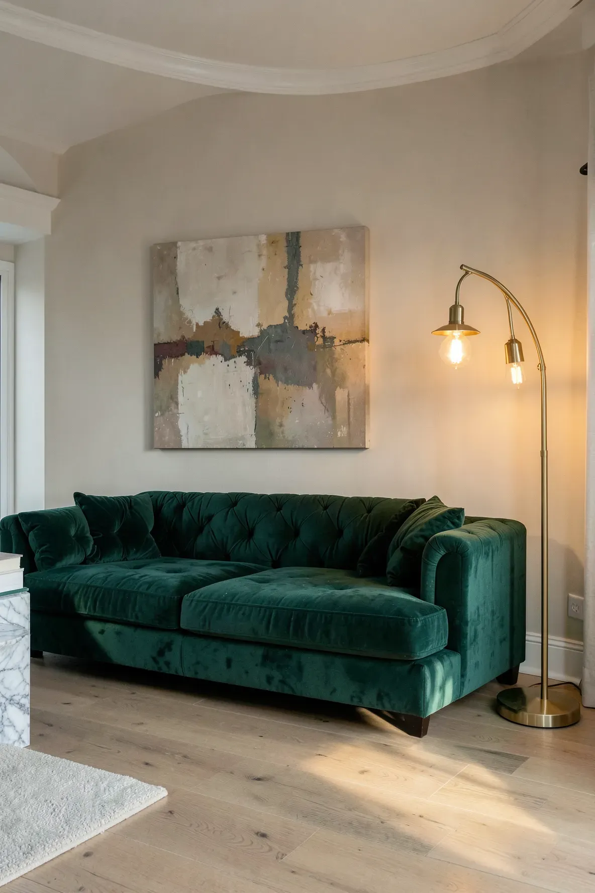 A luxurious emerald green velvet sofa paired with a tall arched brass floor lamp in a cozy room.