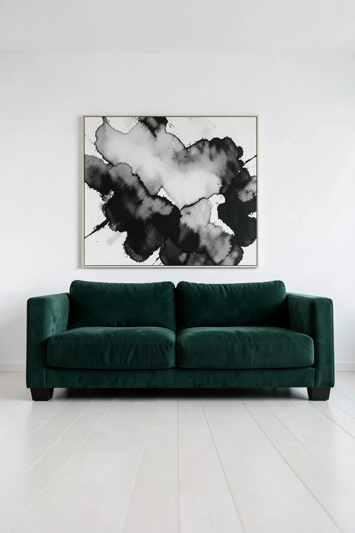 A minimalist living room with a green couch and a large black and white abstract painting.
