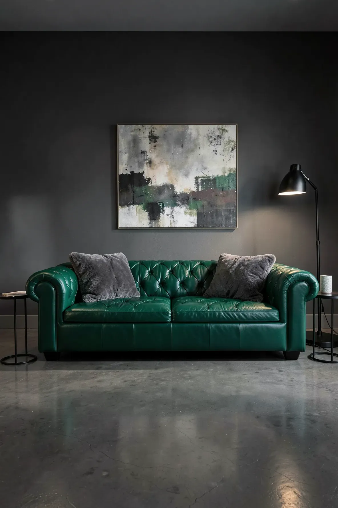 An emerald green tufted Chesterfield sofa with charcoal grey pillows in a modern grey living room.