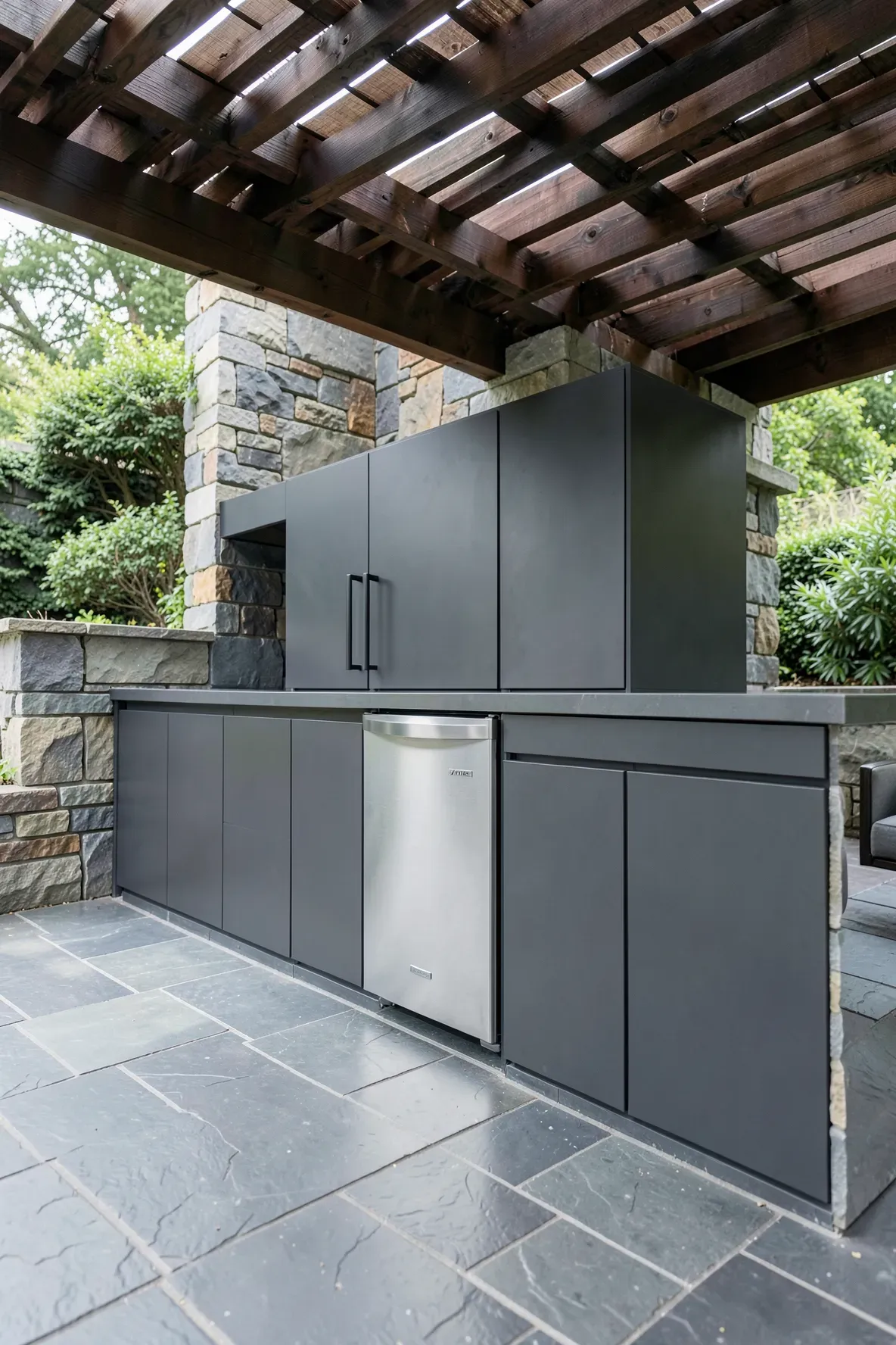Modern charcoal weatherproof cabinets with a built-in stainless steel mini fridge under a covered patio.