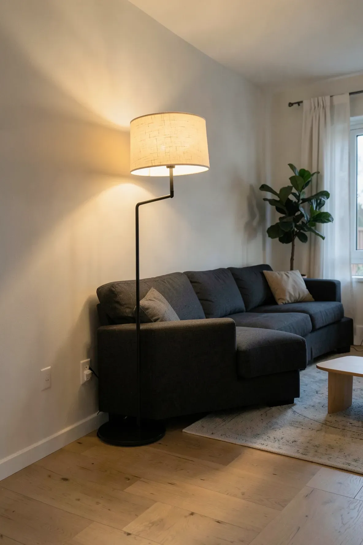 A modern living room featuring a tall floor lamp with a cream fabric shade casting warm light.