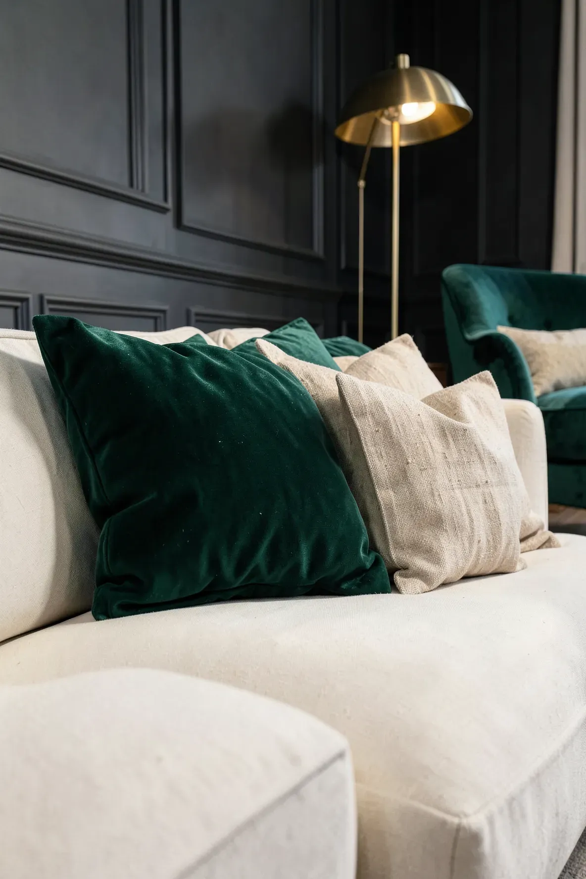 Emerald velvet and beige linen pillows paired together on a cream sofa in a luxury room.
