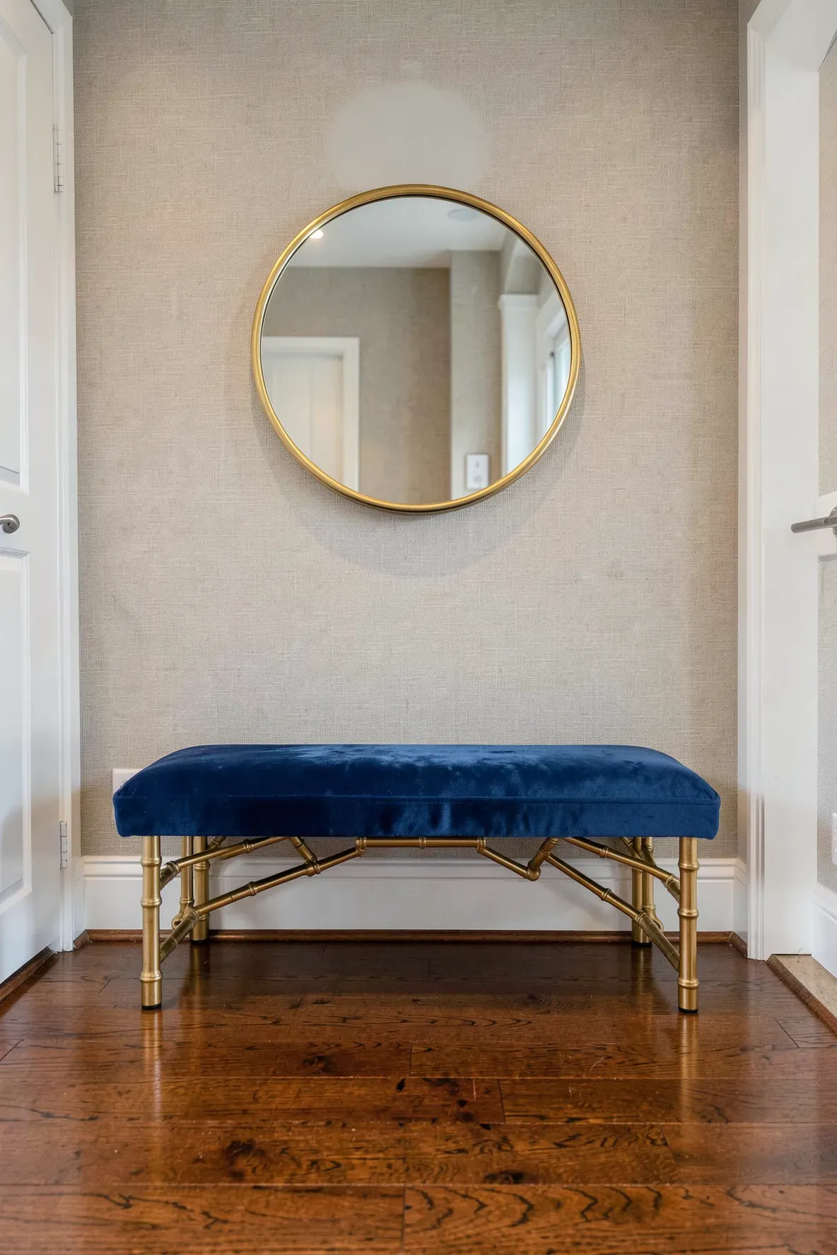 A sapphire blue velvet bench with gold bamboo-style legs in a sophisticated home entryway.