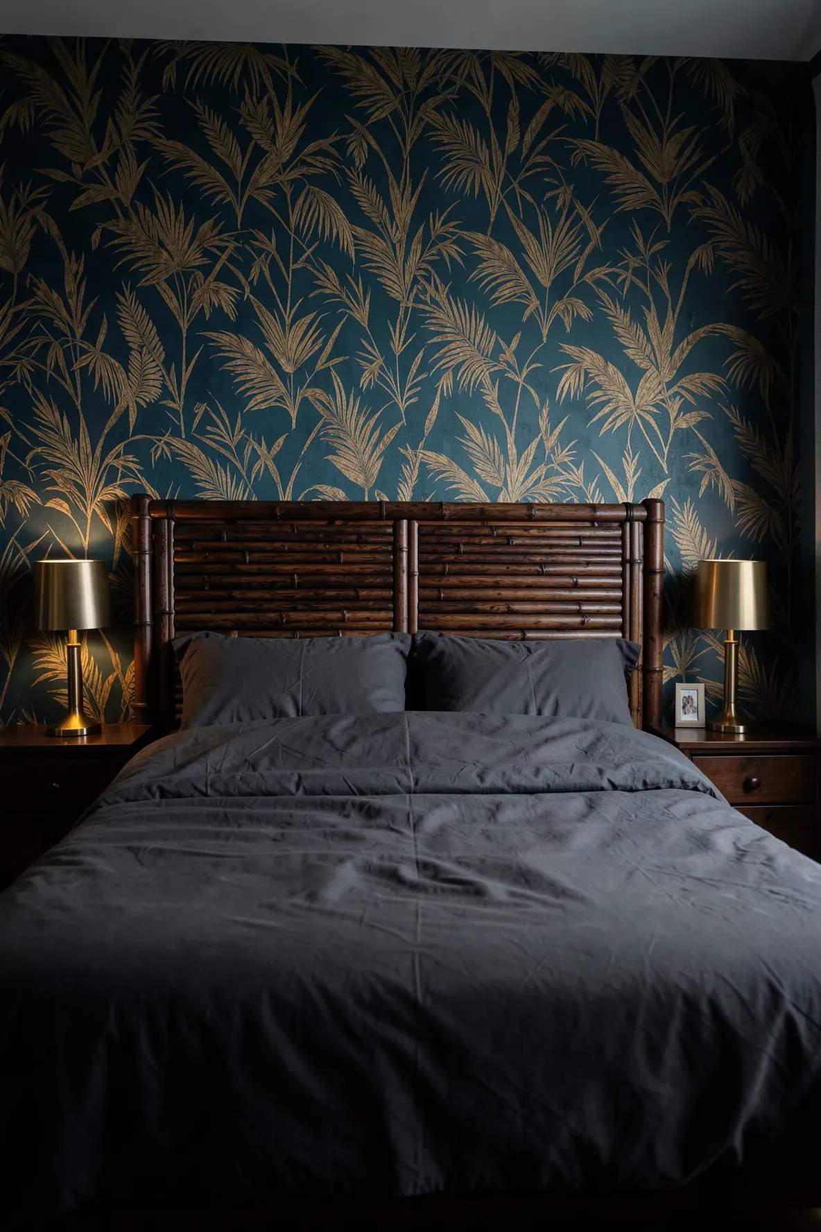 Dark-stained espresso bamboo headboard against a bold tropical wallpaper in a moody bedroom.