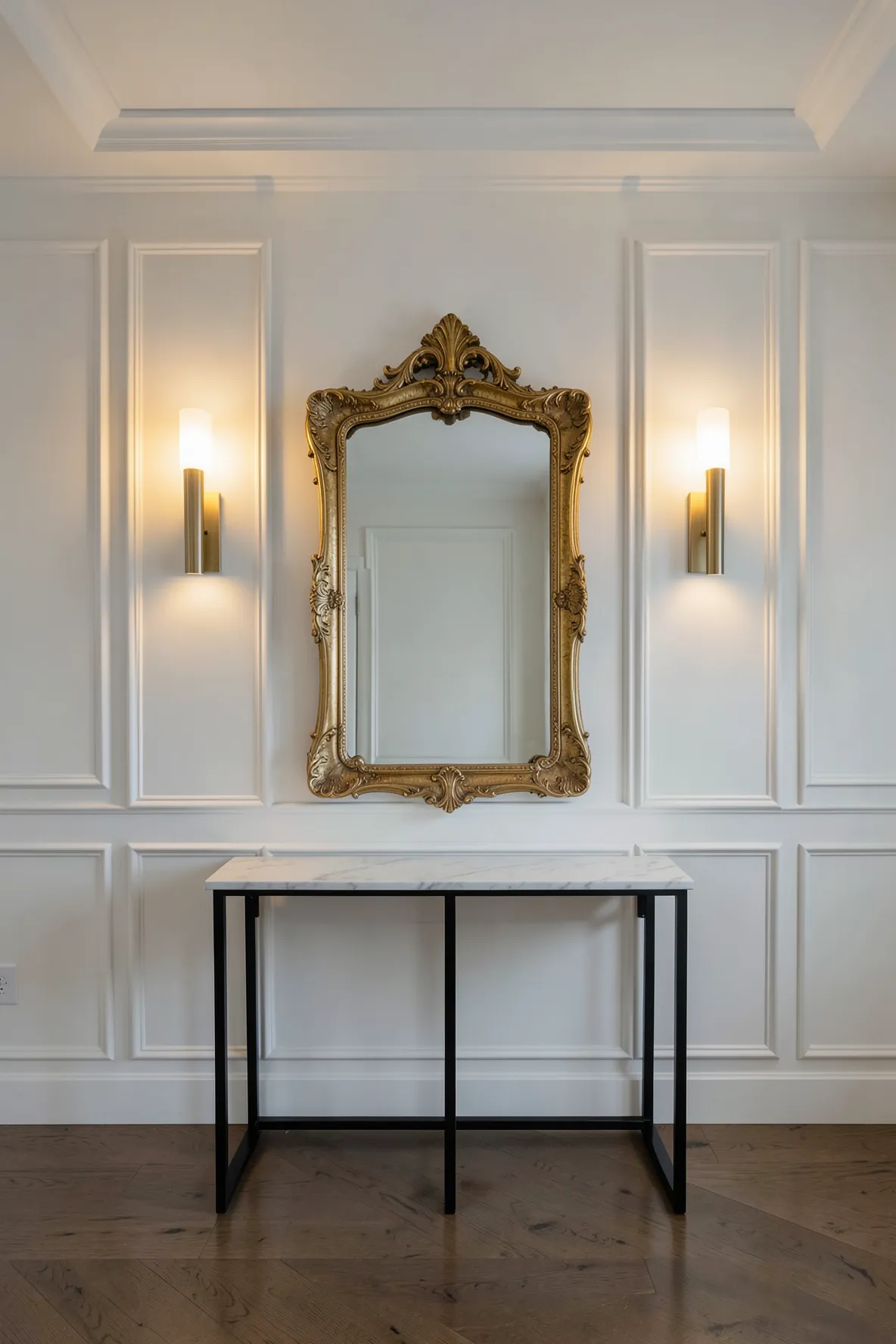 Symmetrical brass sconces flanking a large mirror over a marble console table in a formal foyer.