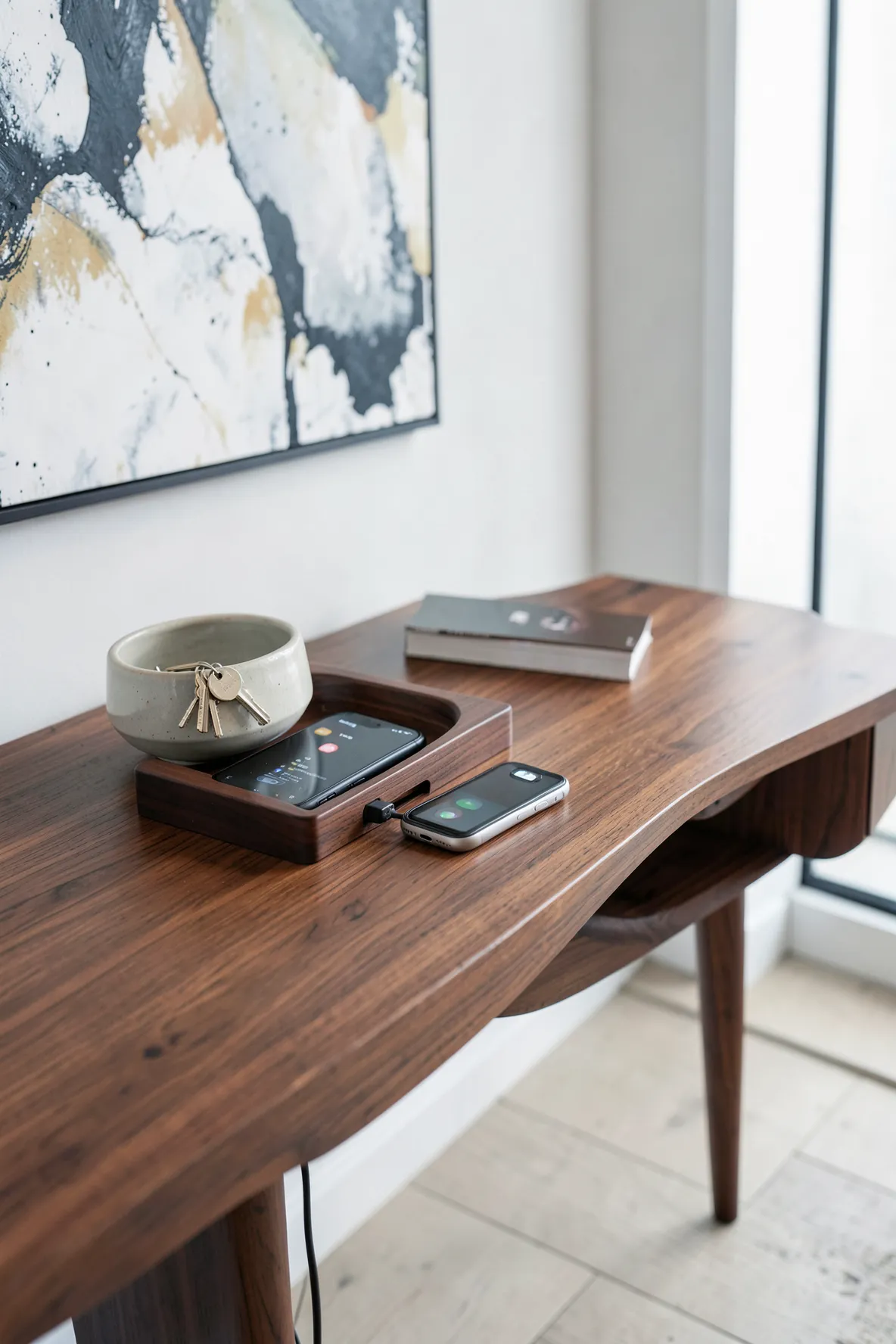 A modern walnut charging station and key bowl on a console table in a tidy entryway.