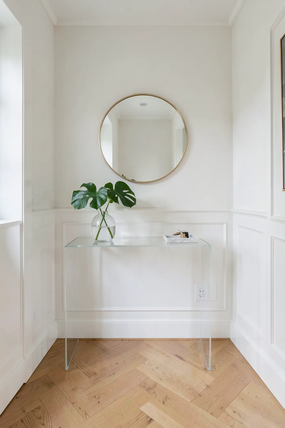 A transparent acrylic console table decorated with a vase in a small modern entrance.