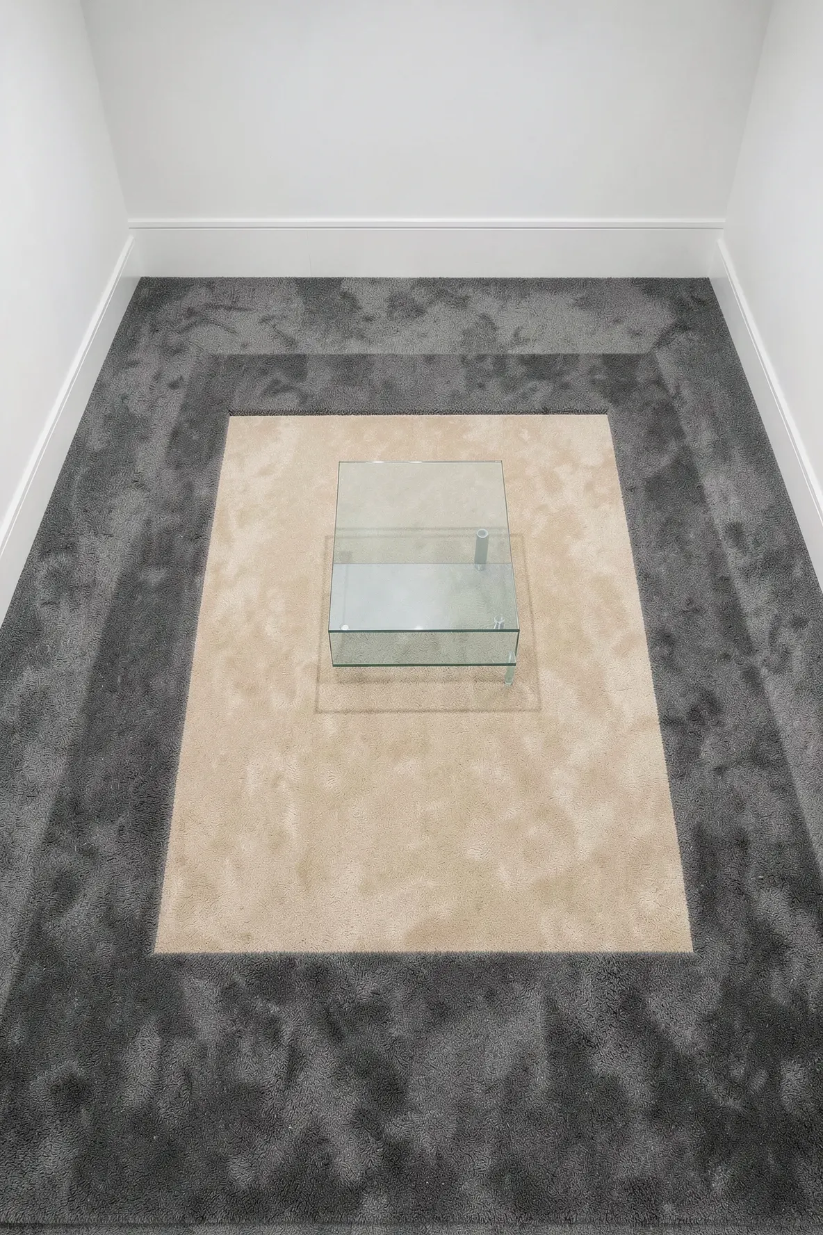 A living room floor featuring a gray carpet border around a central beige carpet section.
