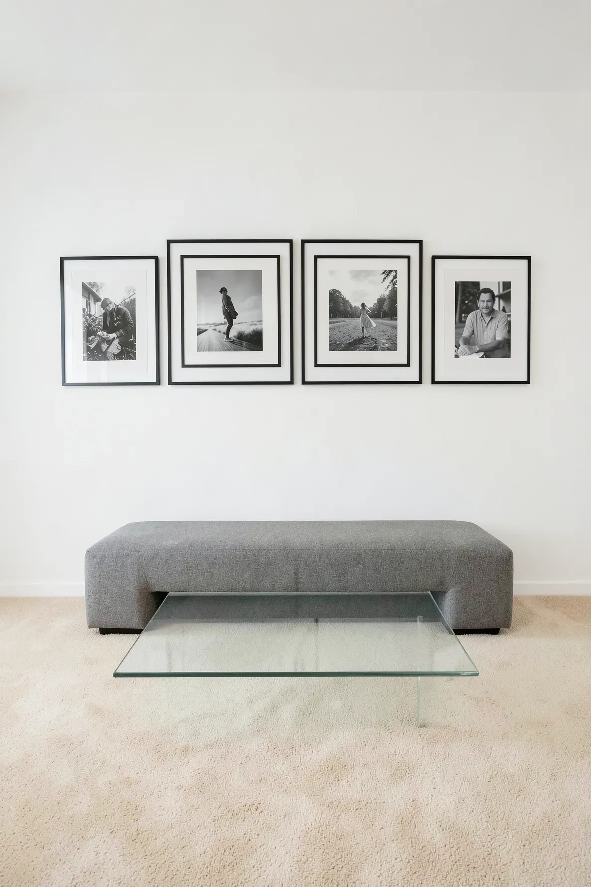 A minimalist gallery wall with black frames in a room with low-pile beige carpet.