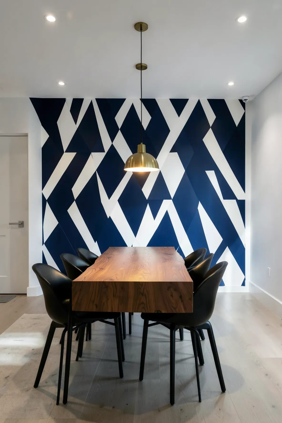 A dining room featuring a navy and white geometric triangle pattern wallpaper accent wall.