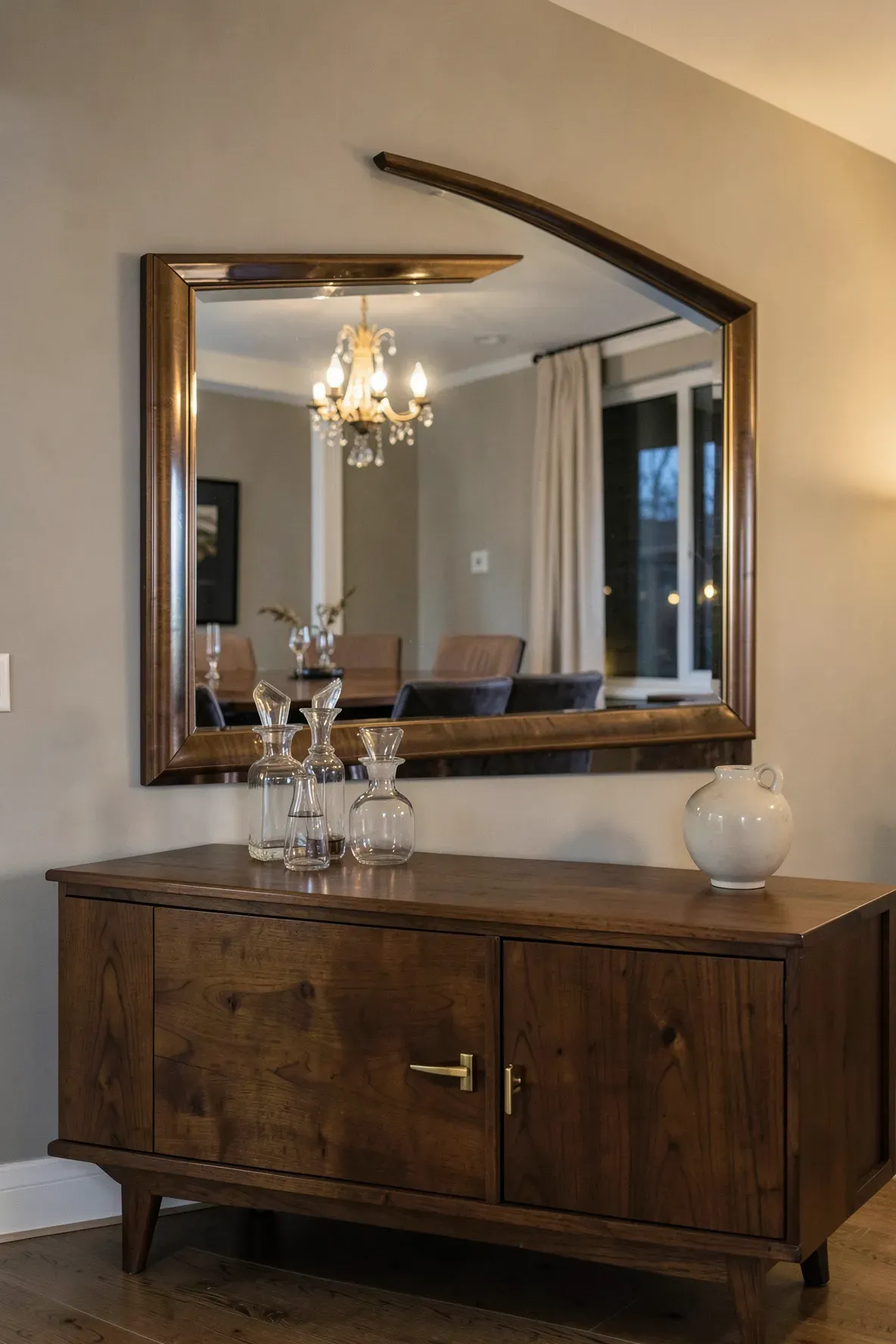 A long beveled edge mirror hung horizontally over a wooden sideboard in a dining room.